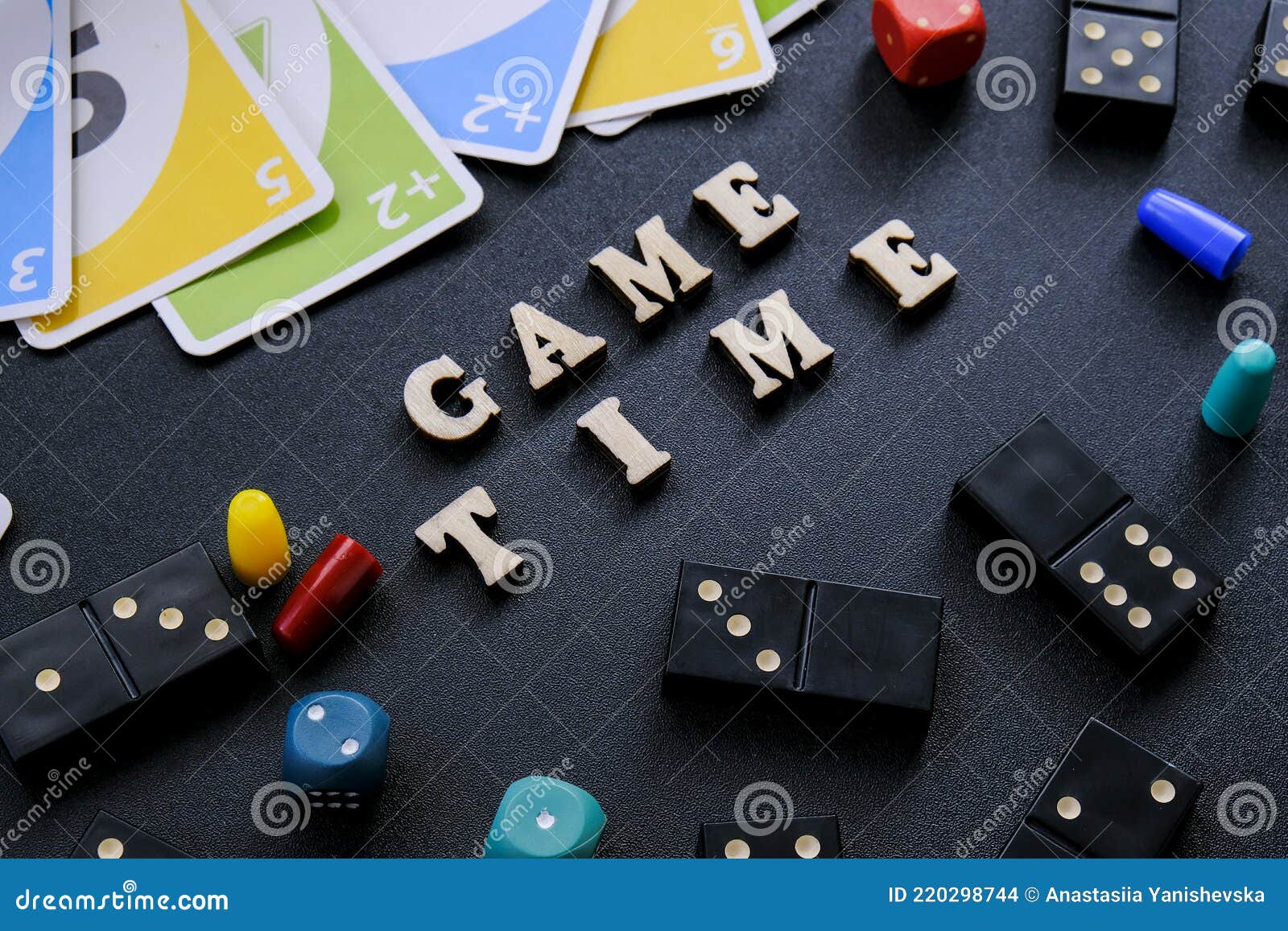 kiev ukraine - 10.03.21 text game time spelled out in wooden letter. surrounded by dice, dominoes uno playing cards on