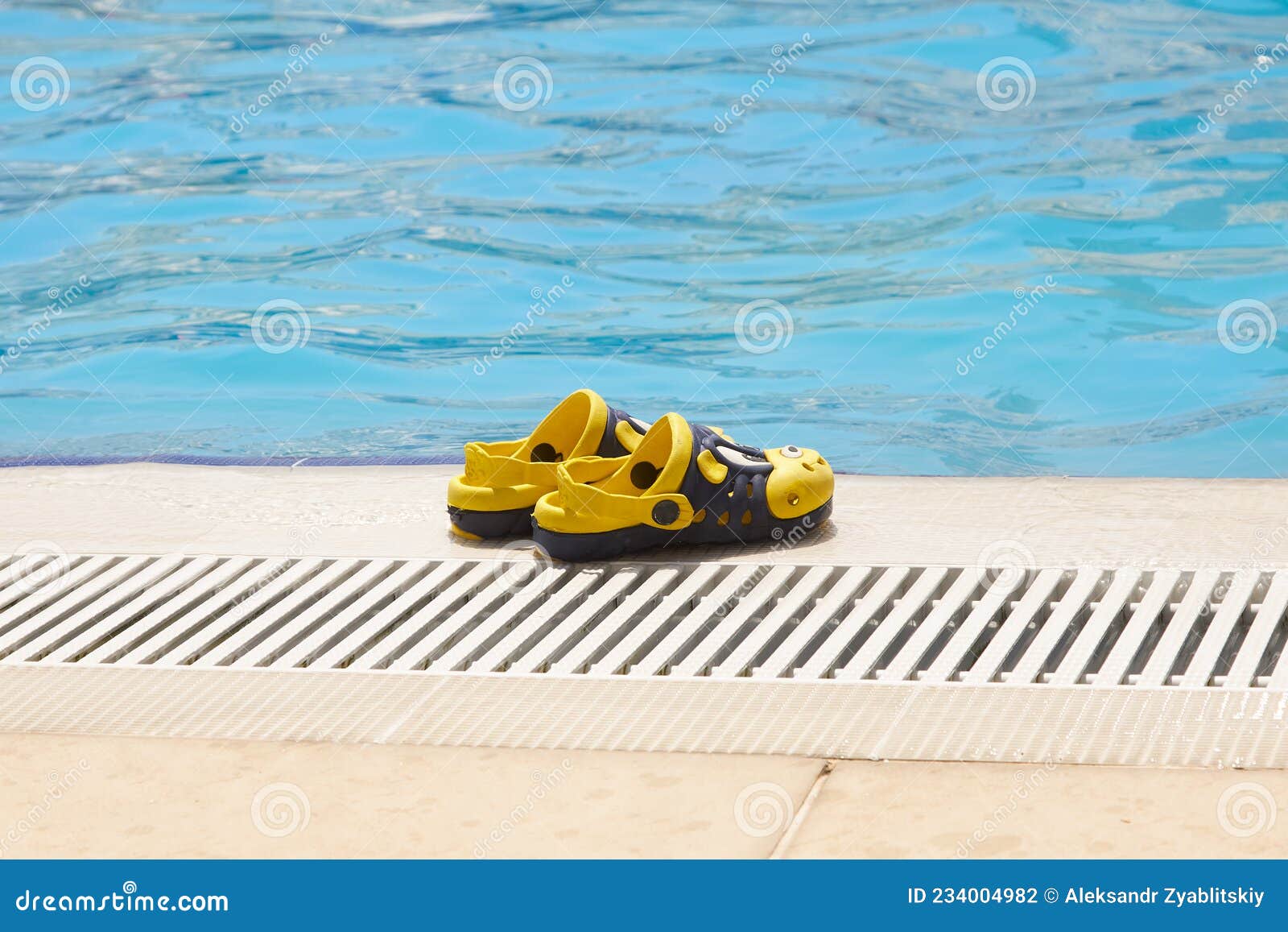 Kinder-Hausschuhe stehen am Pool. Schöne, gelbe Hausschuhe stehen am Pool. Kinder und Schwimmen im Pool