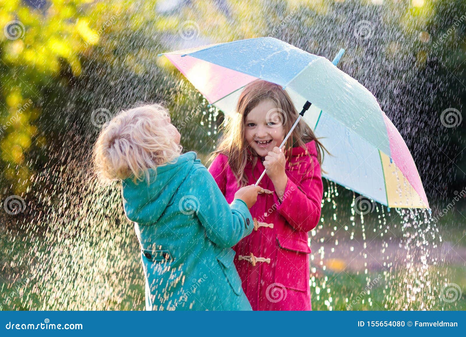 kinder mit dem regenschirm der im herbstduschregen spielt