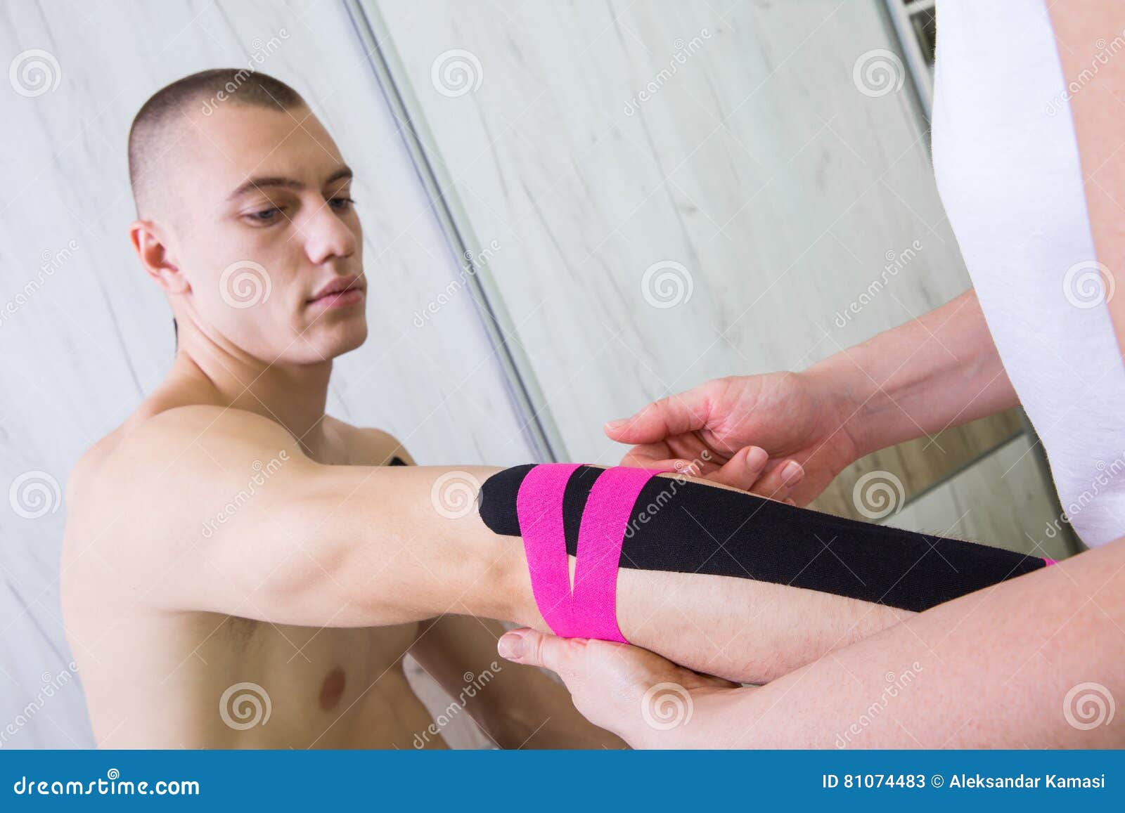 Female physiotherapist putting kinesio tape on patients hand