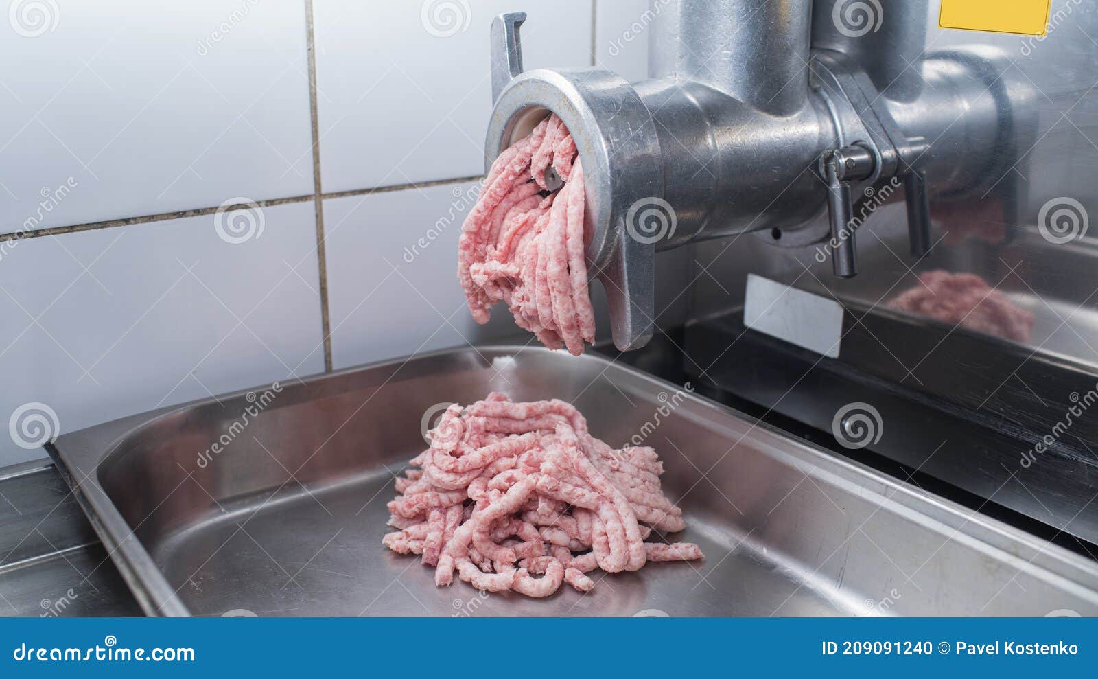 In the Kitchen Creating Minced Pork Meat through a Meat Grinder. Stock