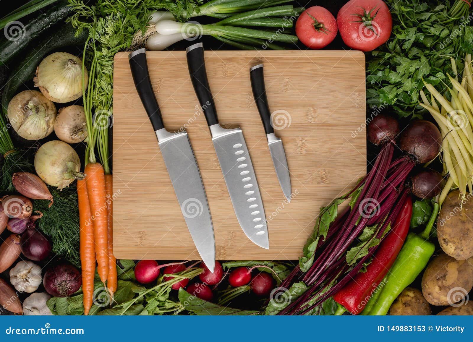 kitchen knives set on wood cutting board with fresh vegetables