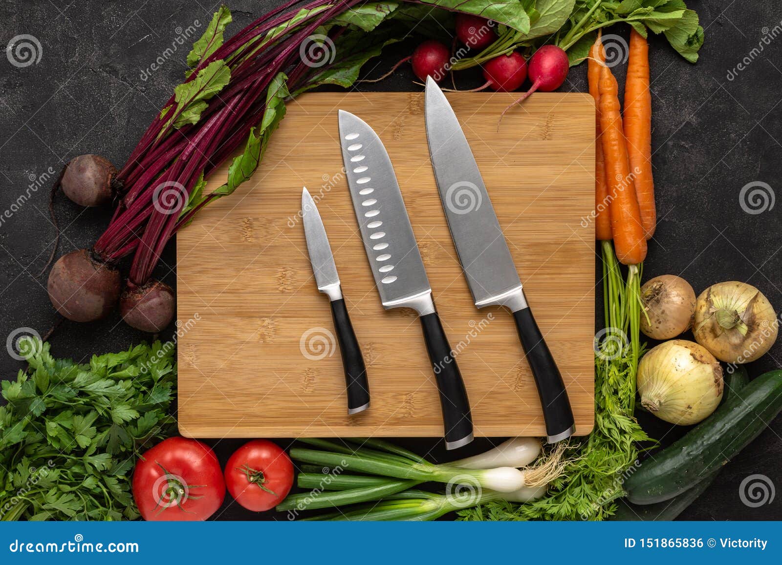 kitchen knives on wooden chopping board with fresh vegetables background. vegetarian raw food.