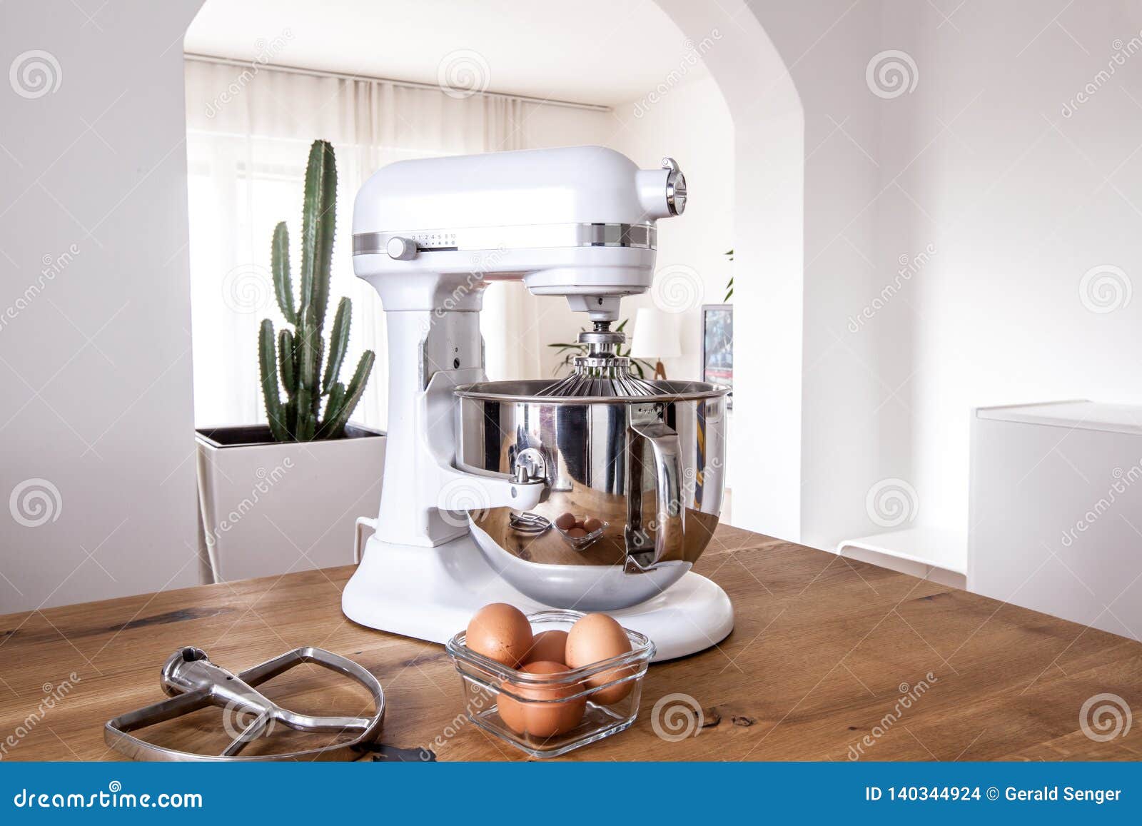 white kitchen machine and stand mixer on a wooden table in a bright  apartment