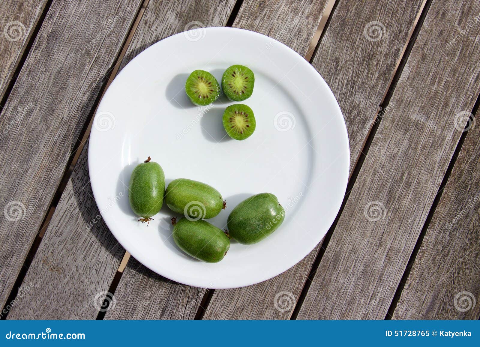 kiwi berries (arctic kiwifruit) on white plate on wooden table