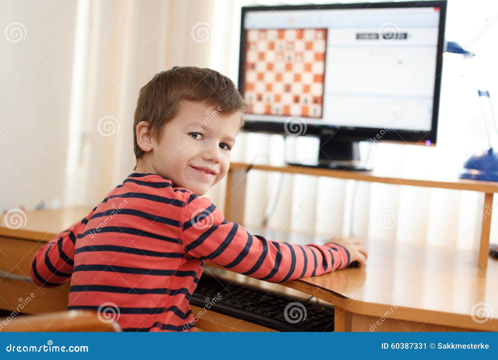 Kleiner Junge, Der Auf Dem PC-Schach Zurück Schaut Spielt Stockbild