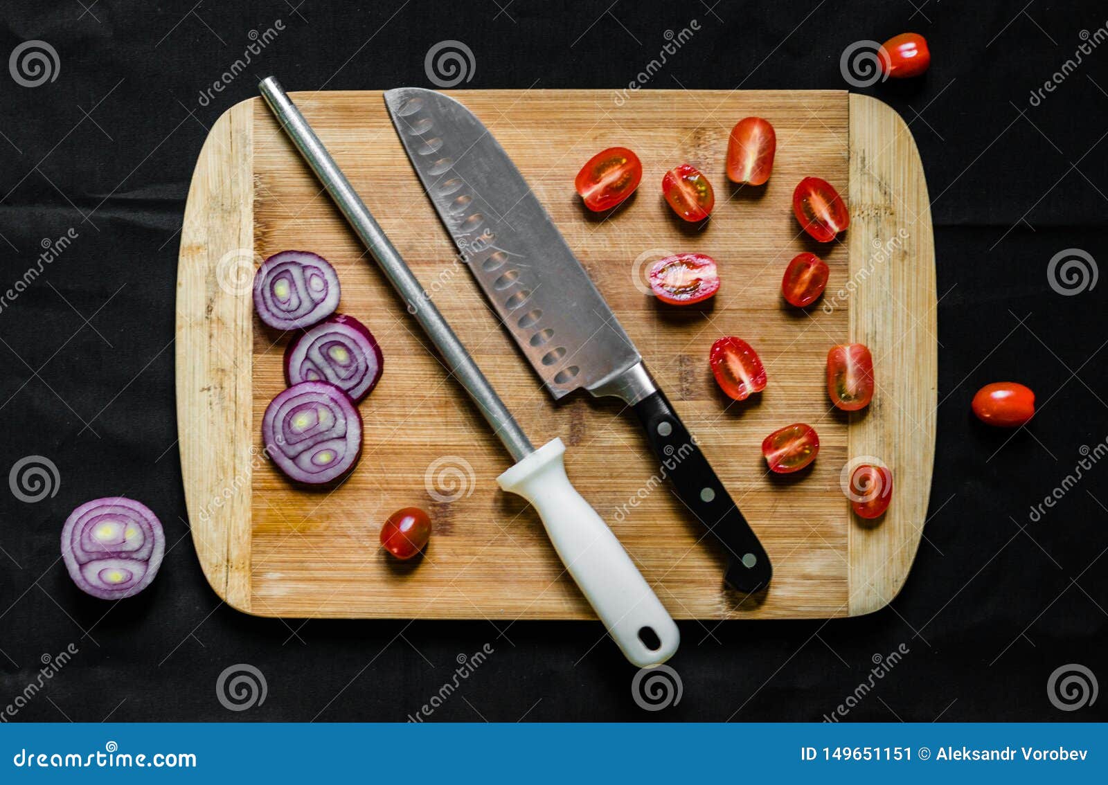 A Knife Sharpener and a Chef Knife on a Cutting Board with Vegetables