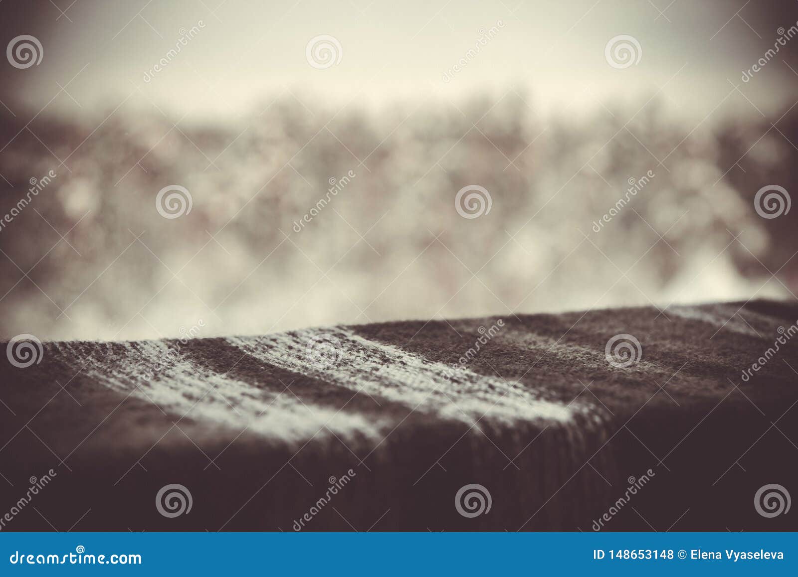 knitted gray texture on the table on a background of blurred winter nature outside the window