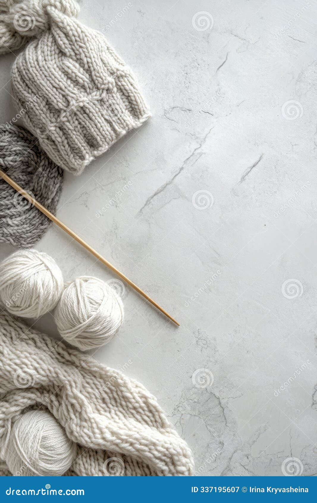 knitting materials including yarn and needles arranged neatly on a marble surface