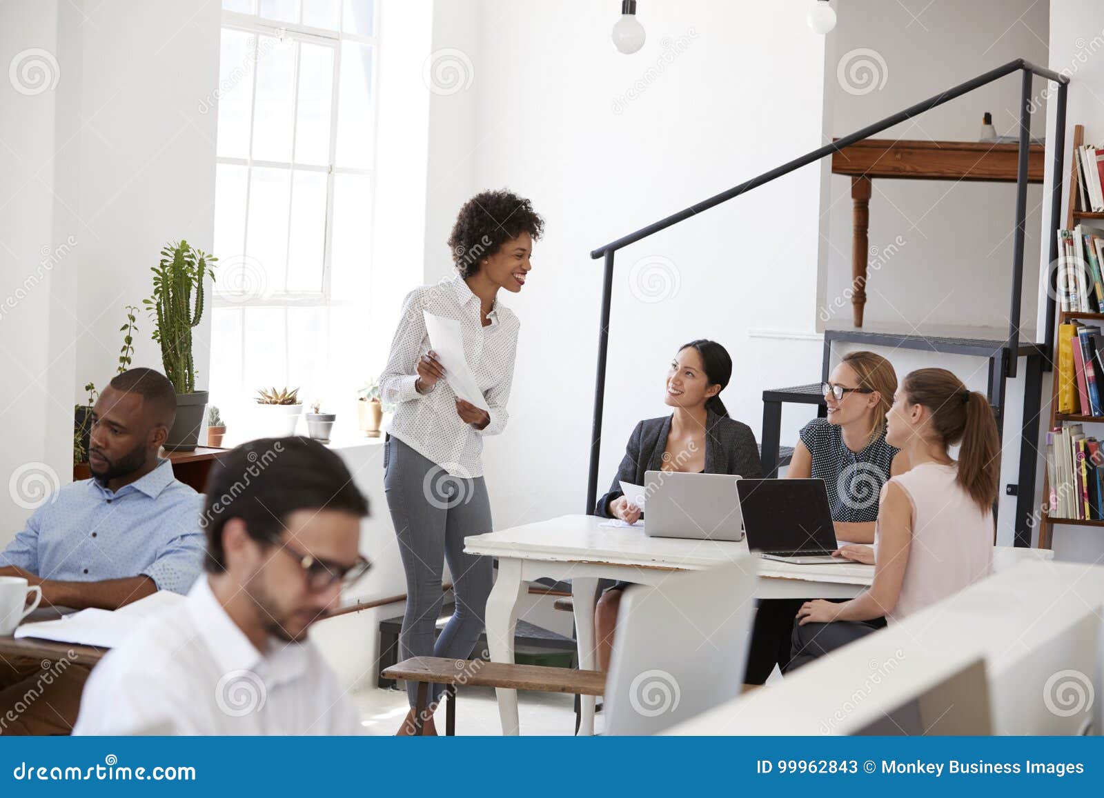 Kobieta przedstawia dokumenty koledzy przy biurkiem w biurze