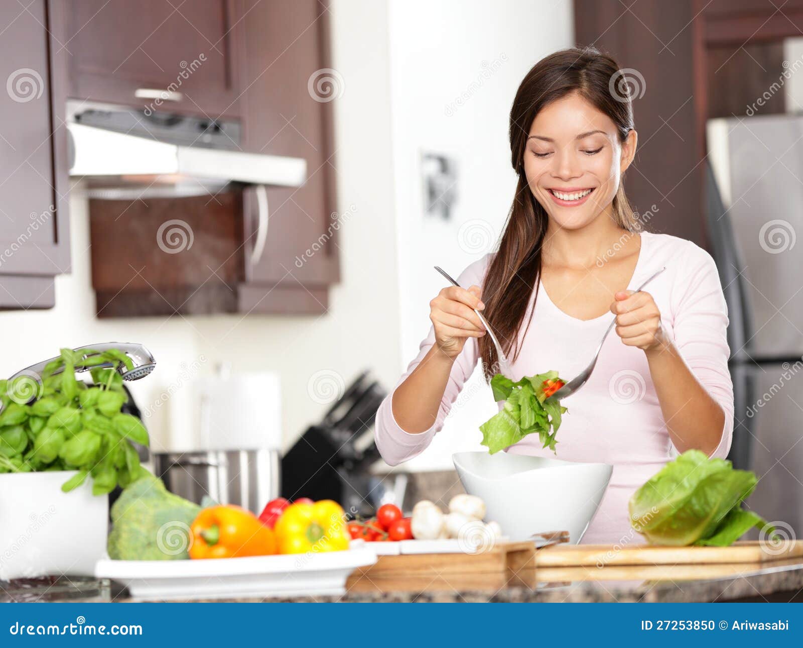 Kobieta robi sałatki w kuchni. Zdrowy łasowania styl życia pojęcie z pięknym młodej kobiety kucharstwem w jej kuchni.