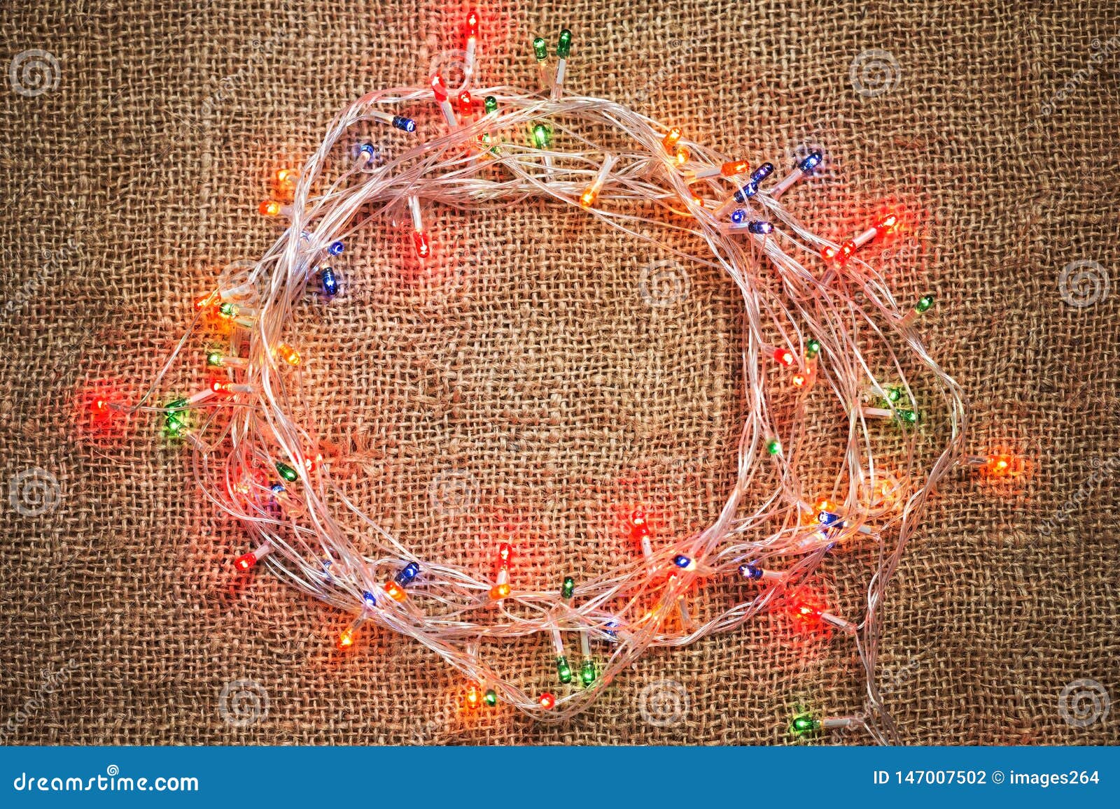 Colorful Christmas light garland on burlap background