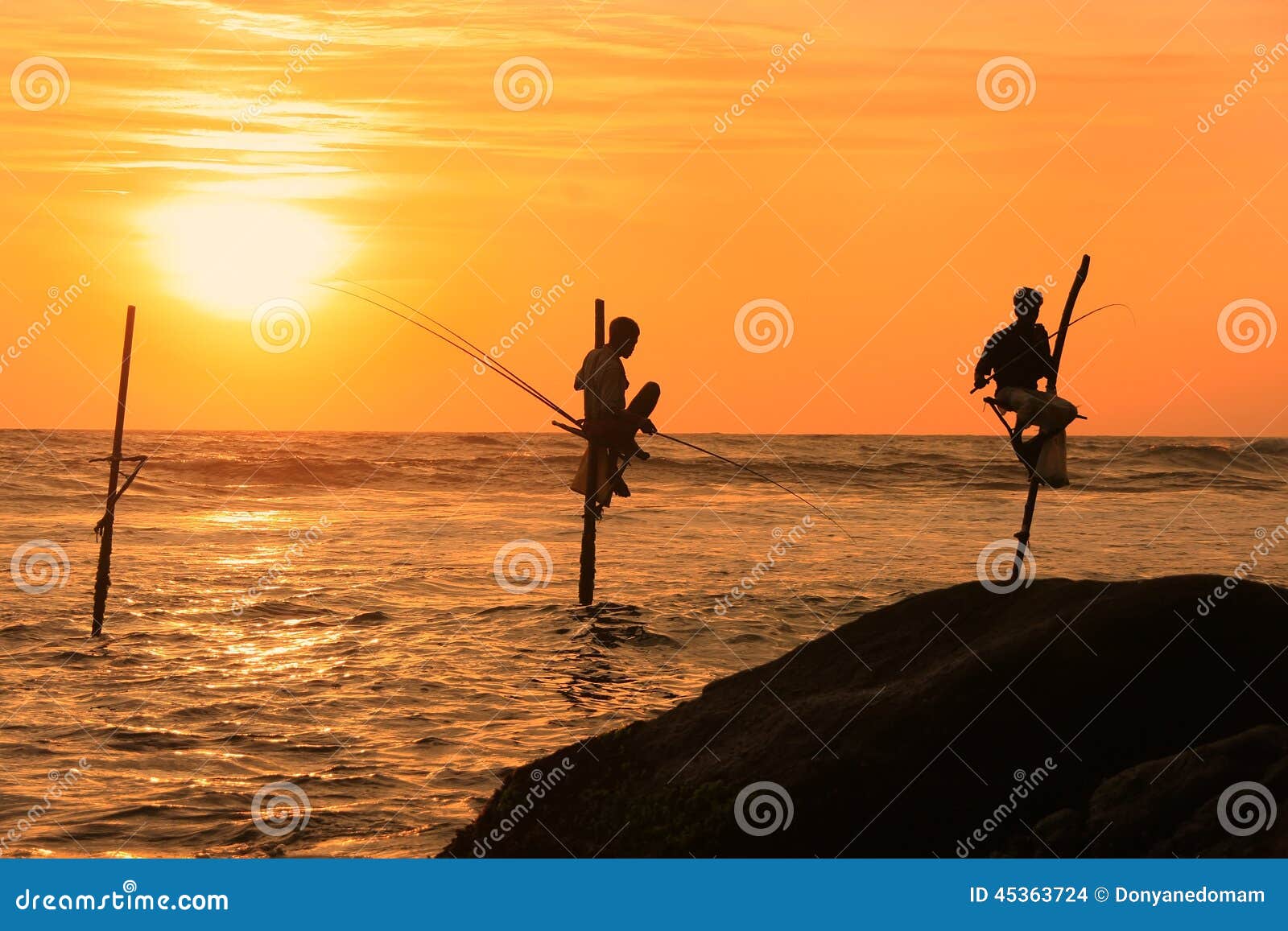 Kontur av fiskare på solnedgången, Unawatuna, Sri Lanka. Kontur av fiskare för en pinne på solnedgången, Unawatuna, Sri Lanka