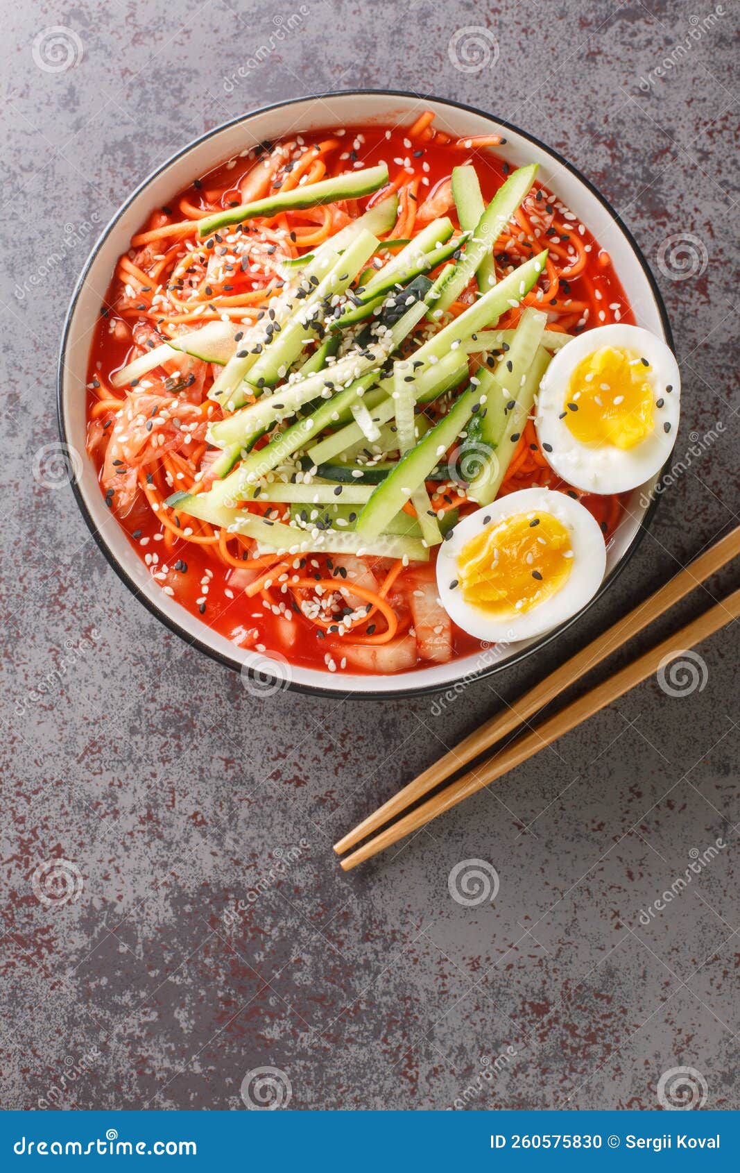 korean food noodles salad bibim guksu in a black bowl closeup. vertical top view