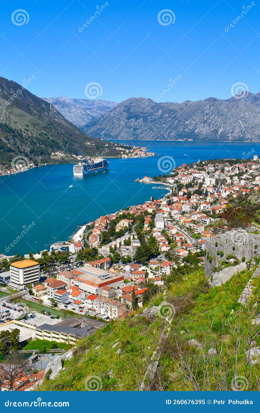 Kotor montenegro europe. baía de kotor no mar adriático. paredes históricas de rochas telhados de prédios da velha cidade. cruzeiro nas montanhas da baía ao fundo. céu azul limpo dia ensolarado.