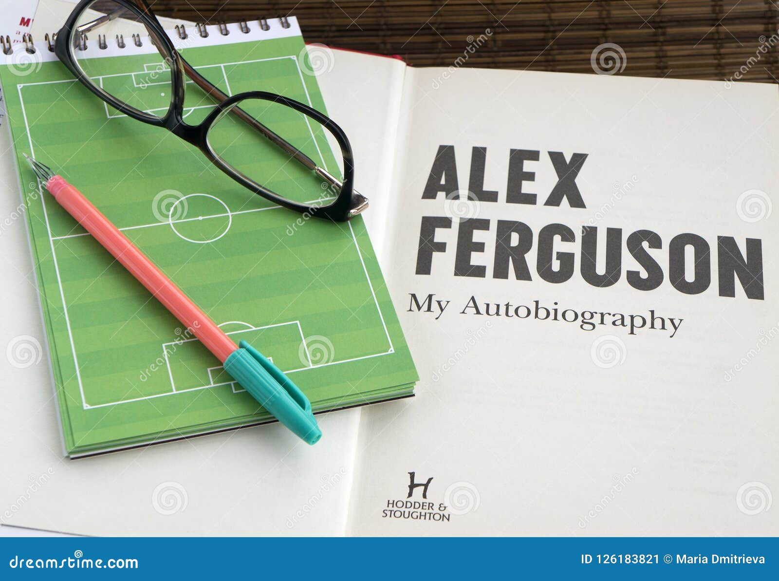 reading autobiography book by alex ferguson, a football coach. glasses