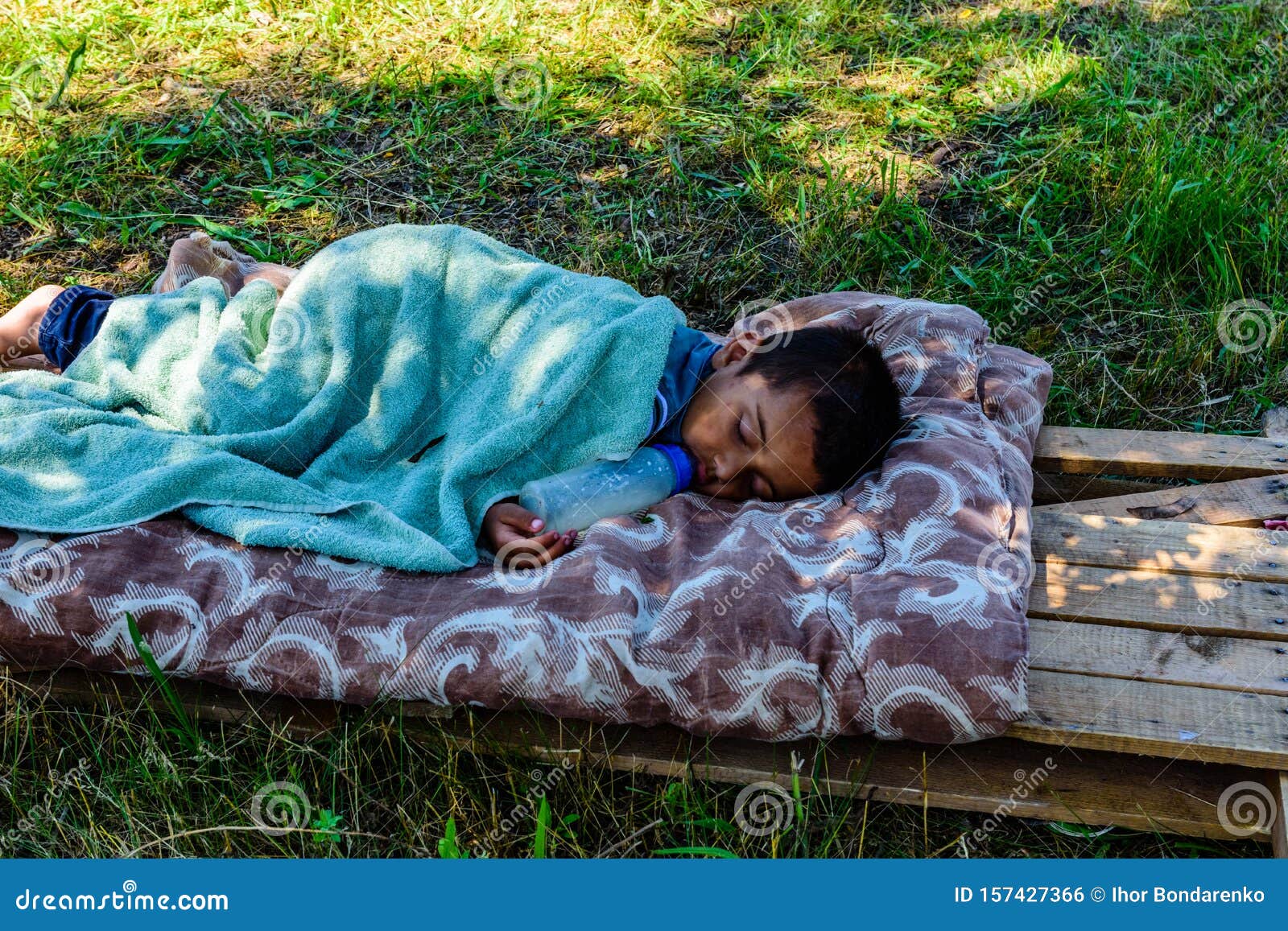 Little gypsy boy with bottle of the milk sleeping. Kremenchug, Ukraine - june 8, 2019: Little gypsy boy with bottle of milk sleeping