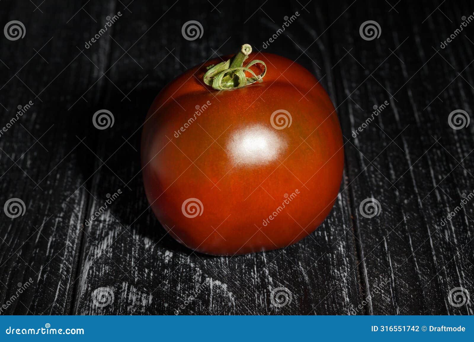 kumato tomato on black wood