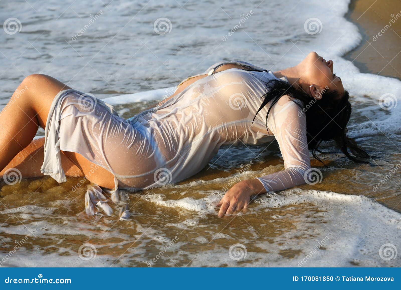 Kvinna i en våtklänning på kusten. Kvinna i en våtklänning vid havets kust