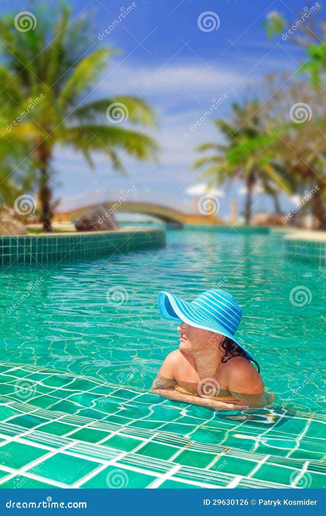 Kvinna i hatt som kopplar av på simbassängen i Thailand