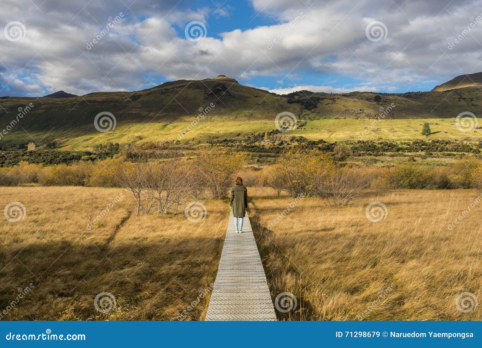 Kvinnan promenerar strandpromenad-/banatraversvåtmarker. Kvinnan promenerar nord för strandpromenad-/banatraversvåtmarker precis av Glenorchy, Nya Zeeland