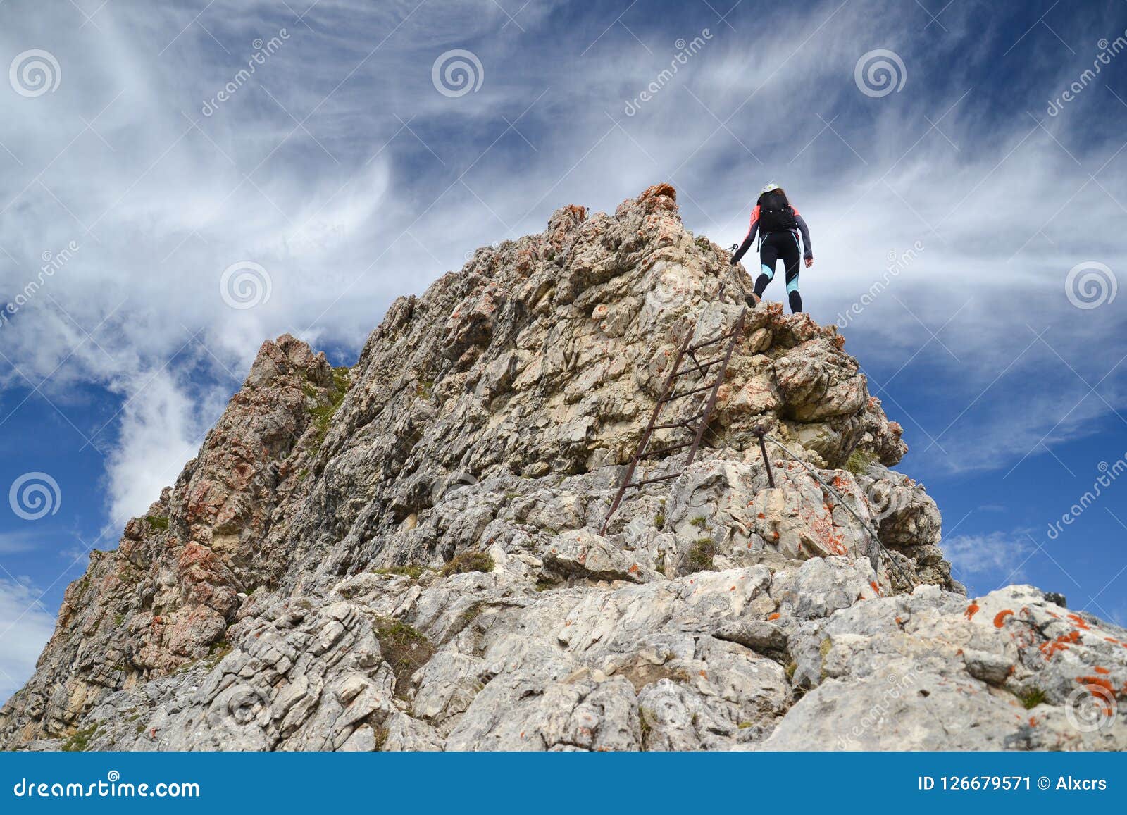 Kvinnlig klättrare på Dolomitesberg. Uppåtriktad sikt av en klättrare för ung kvinna på a via ferratarutten till ett maximum i Dolomitesbergen, Italien