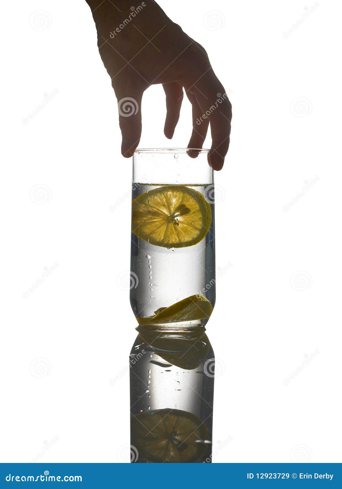 L'eau avec le citron et la main. La main d'un femme retenant une glace de l'eau avec le citron, sur un positionnement r3fléchissant de blanc.