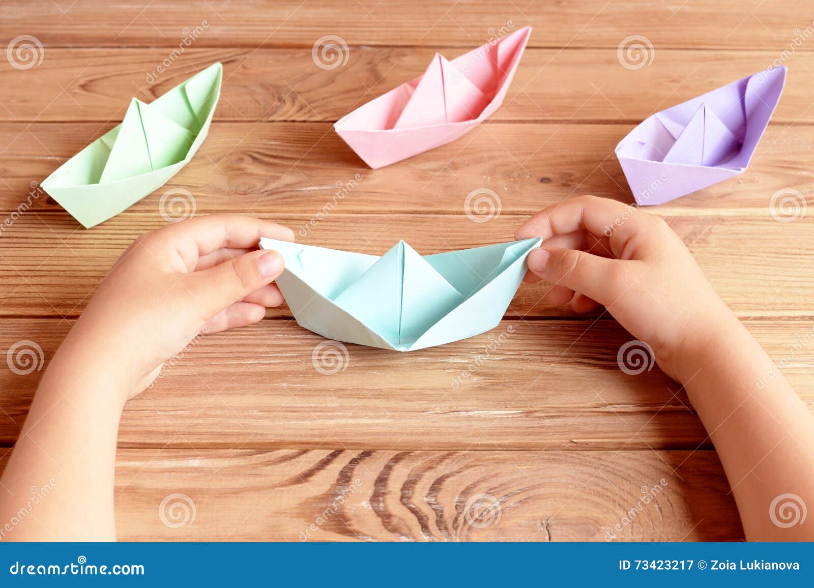 L'enfant Tient L'origami Se Transportent Dans Des Ses Mains Pliage De  Papier D'origami Coloré De Bateaux Sur Une Table En Bois Image stock -  Image du prise, prises: 73423217