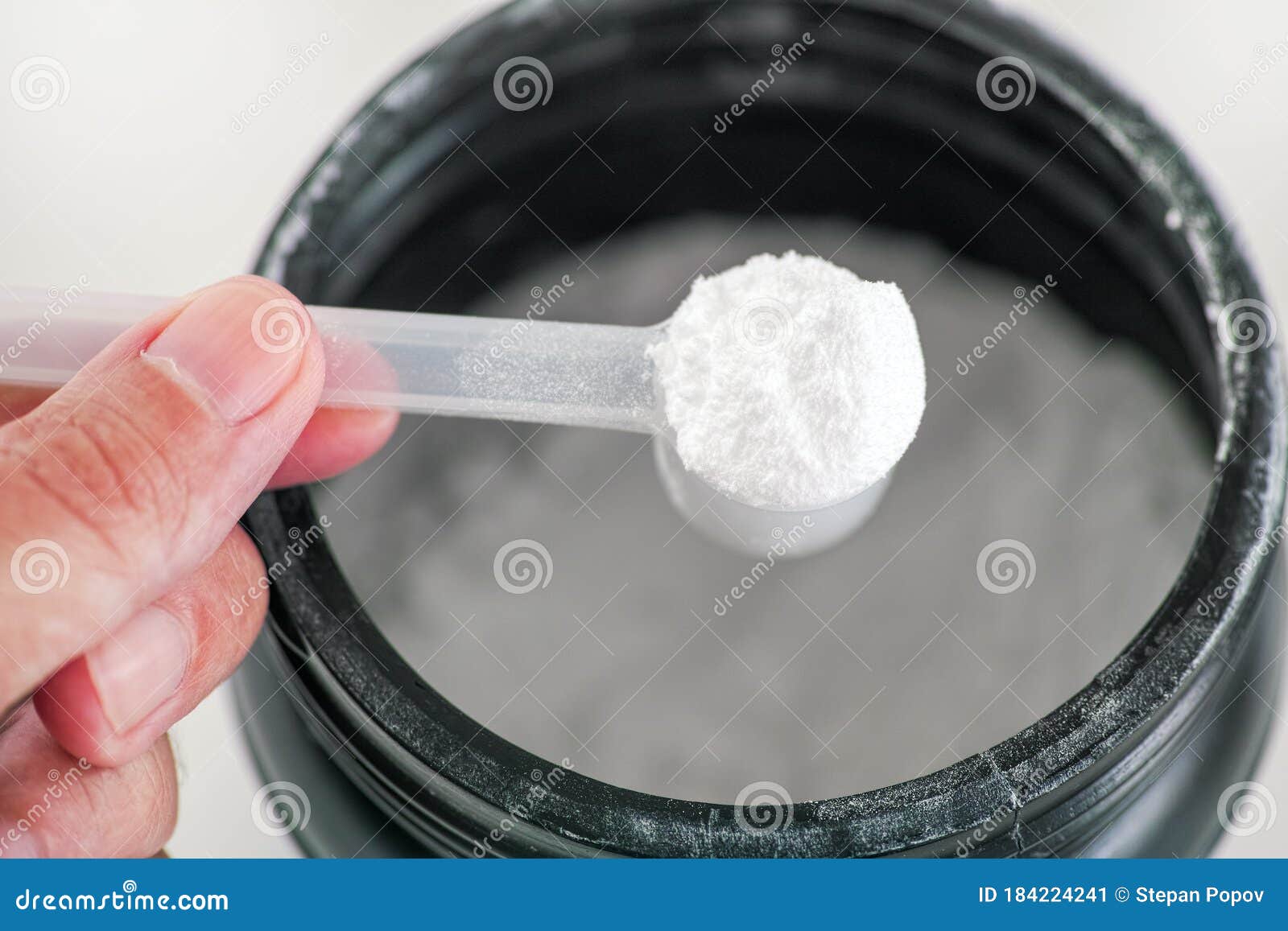 l-glutamine supplement. man holding scoop with l-glutamine powder inside