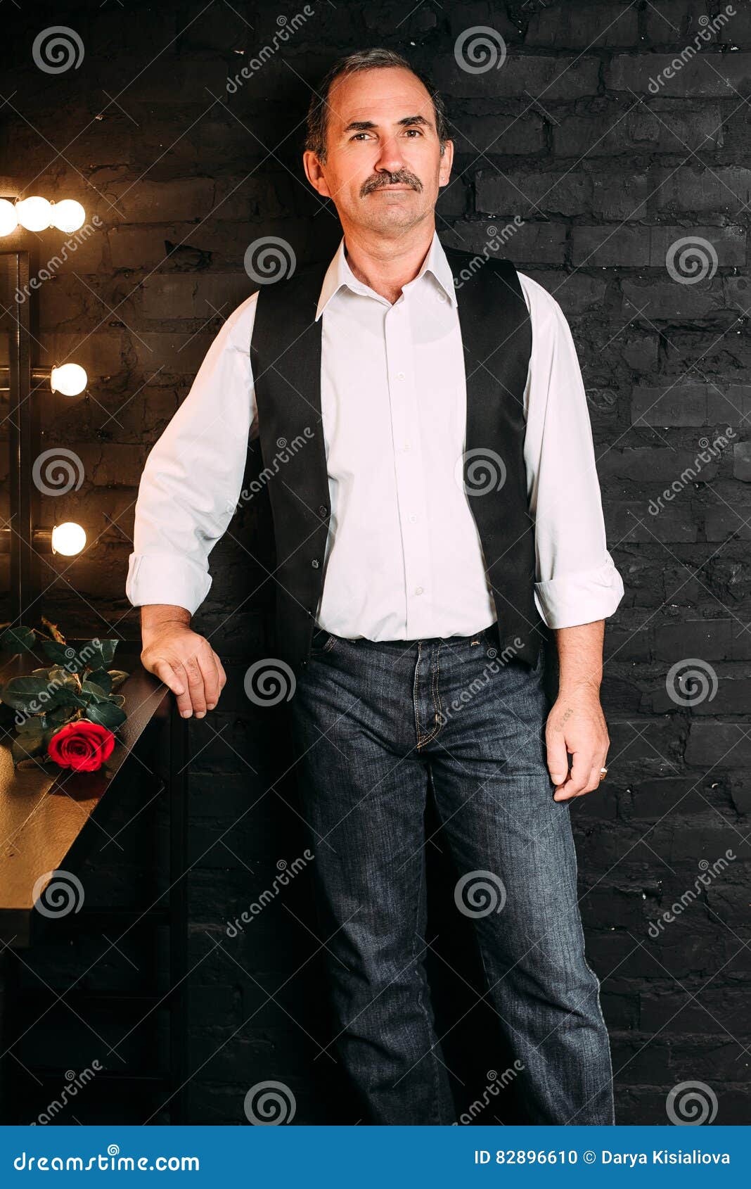 L'homme âgé Par Milieu Beau Est Habillé Dans Une Chemise Blanche Et Un Gilet  Noir, Tenant Une Fleur Rouge De Rose, Célibataire Fo Photo stock - Image du  tony, homme: 82896610