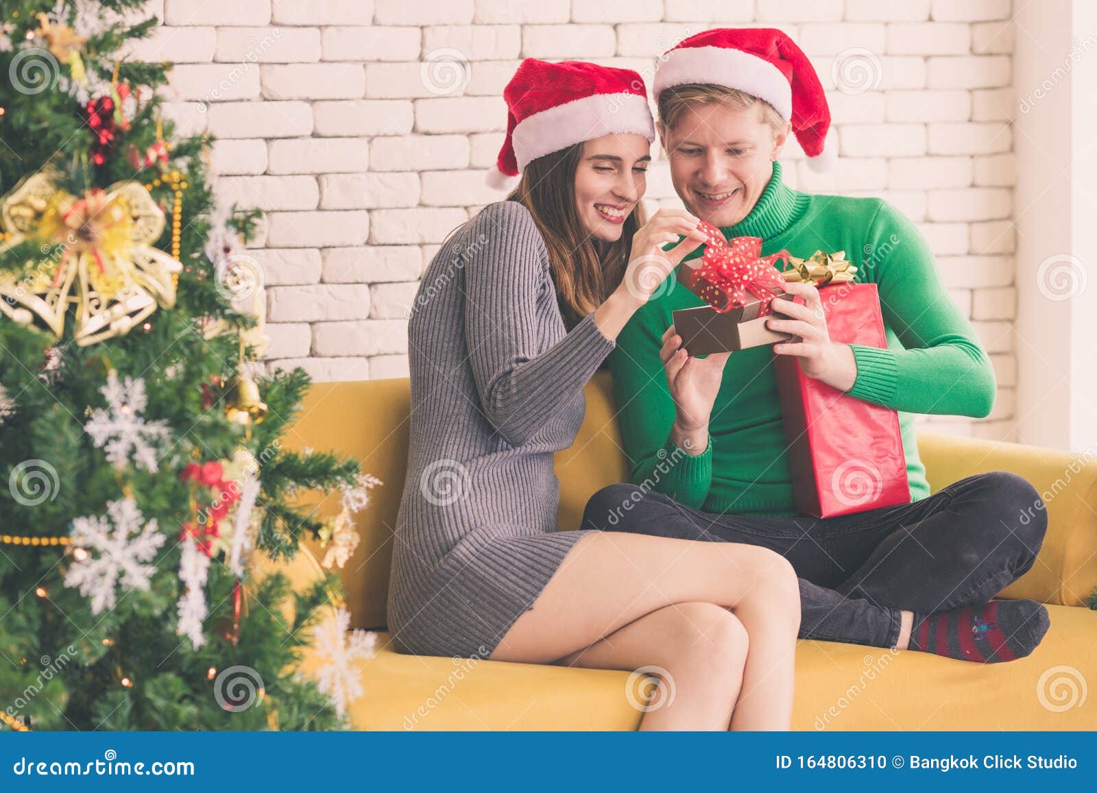 Jeune Couple Assis Près De L'arbre De Noël, Petite Amie Donnant Un