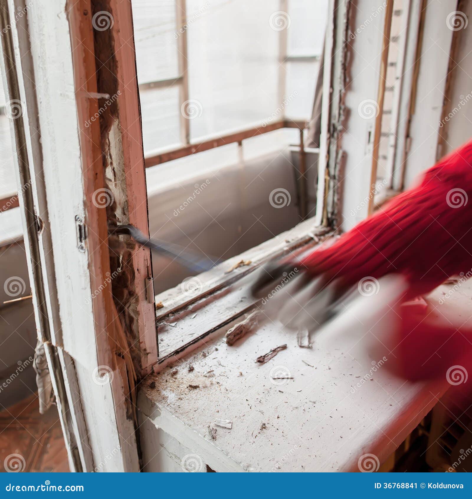 L'installatore che per mezzo del bastone a leva smantella il vecchio fram della finestra. L'installatore in maglione rosso facendo uso del bastone a leva smantella la vecchi struttura della finestra e davanzale