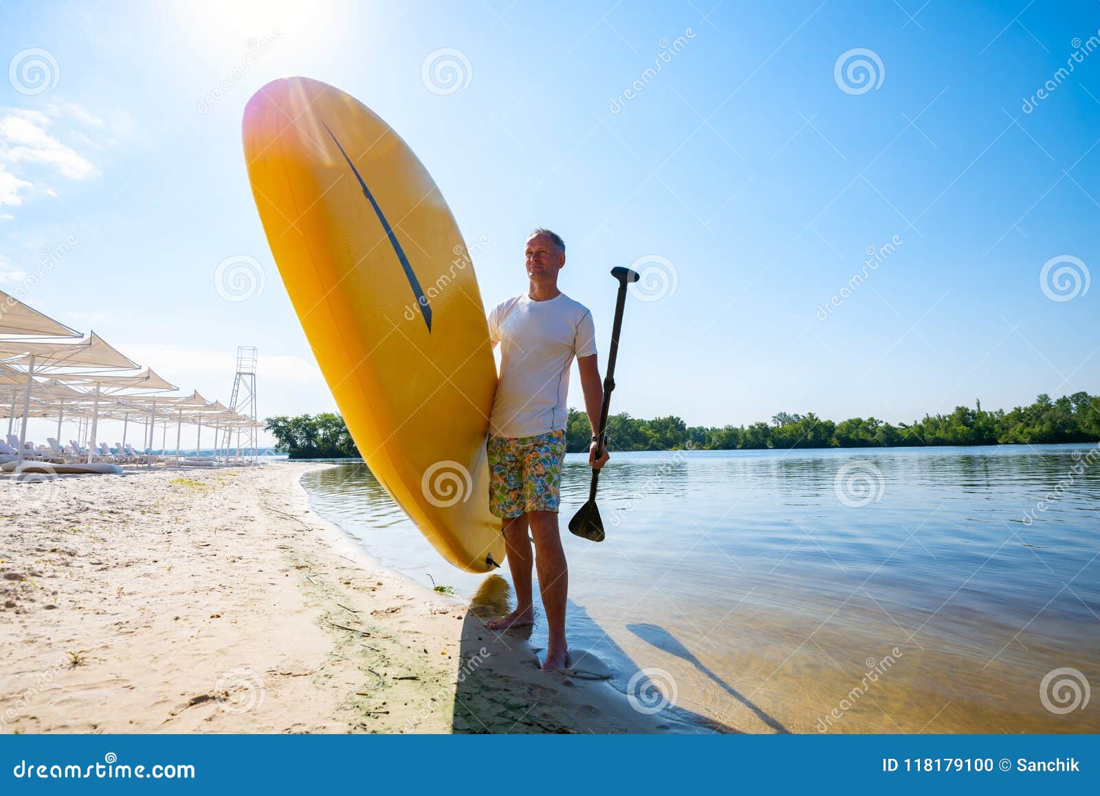 L'uomo Felice Sta Stando Con Un Bordo Del SUP Sulla Spiaggia Fotografia ...