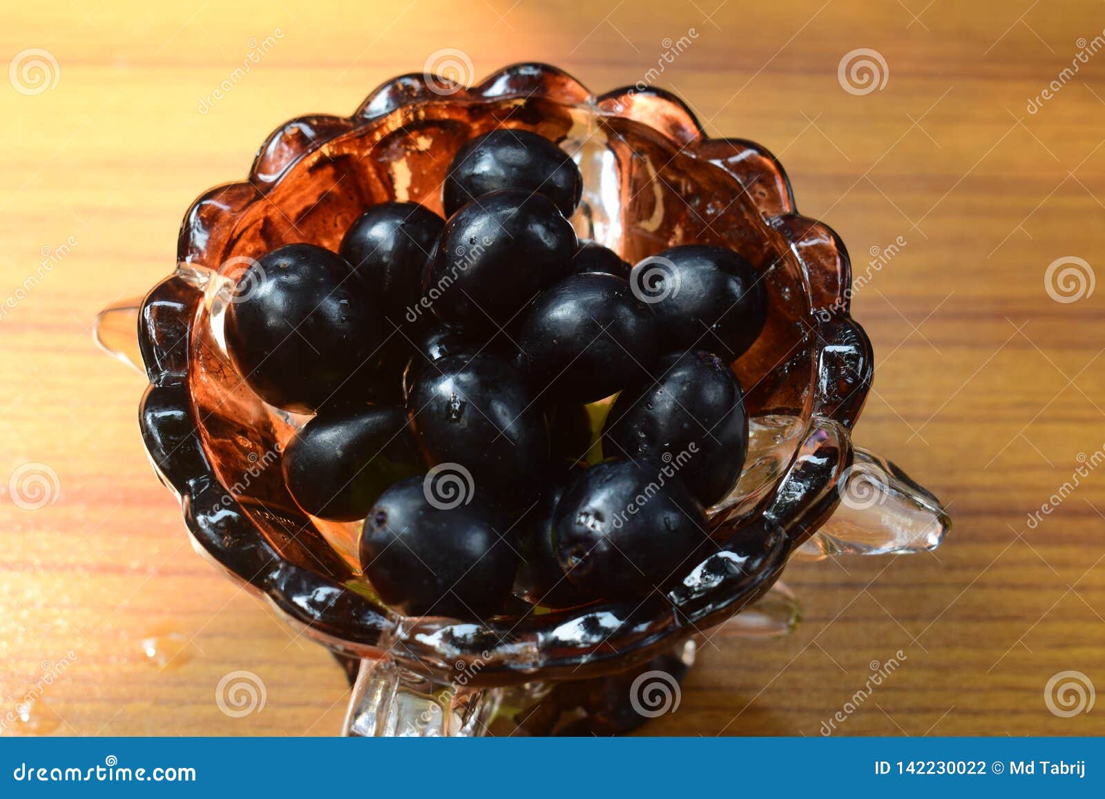 L'uva nera ha sistemato su una ciotola di vetro per la dieta sana ed i buona salute. L'uva ha sistemato nero succoso di buoni del dessert di dieta sana della ciotola di vetro frutti dolci saporiti dell'alimento