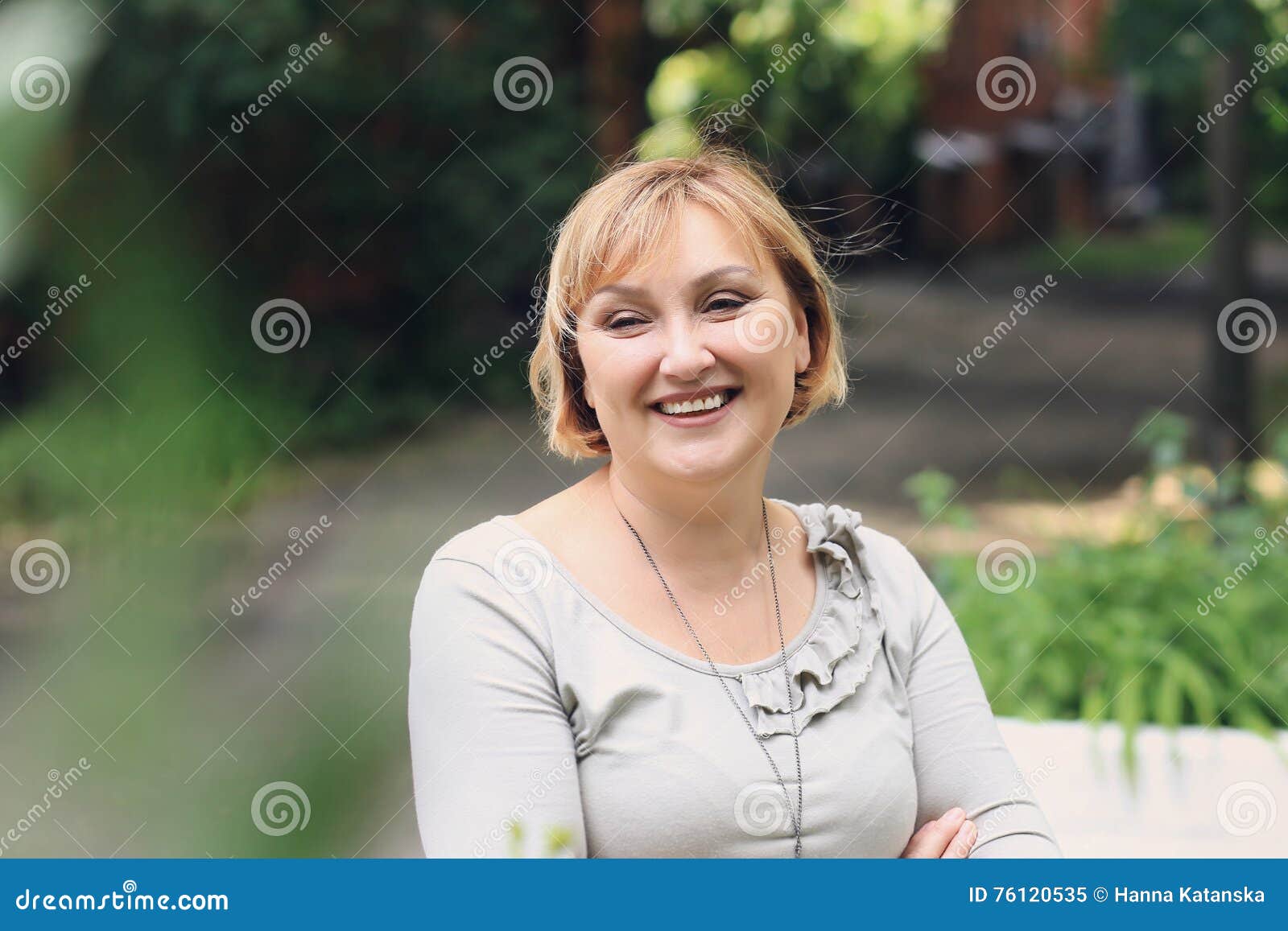 La belle femme est en parc Elle semble partie et sourire Elle a les cheveux blonds d'un dieu, yeux verts, peau blanche