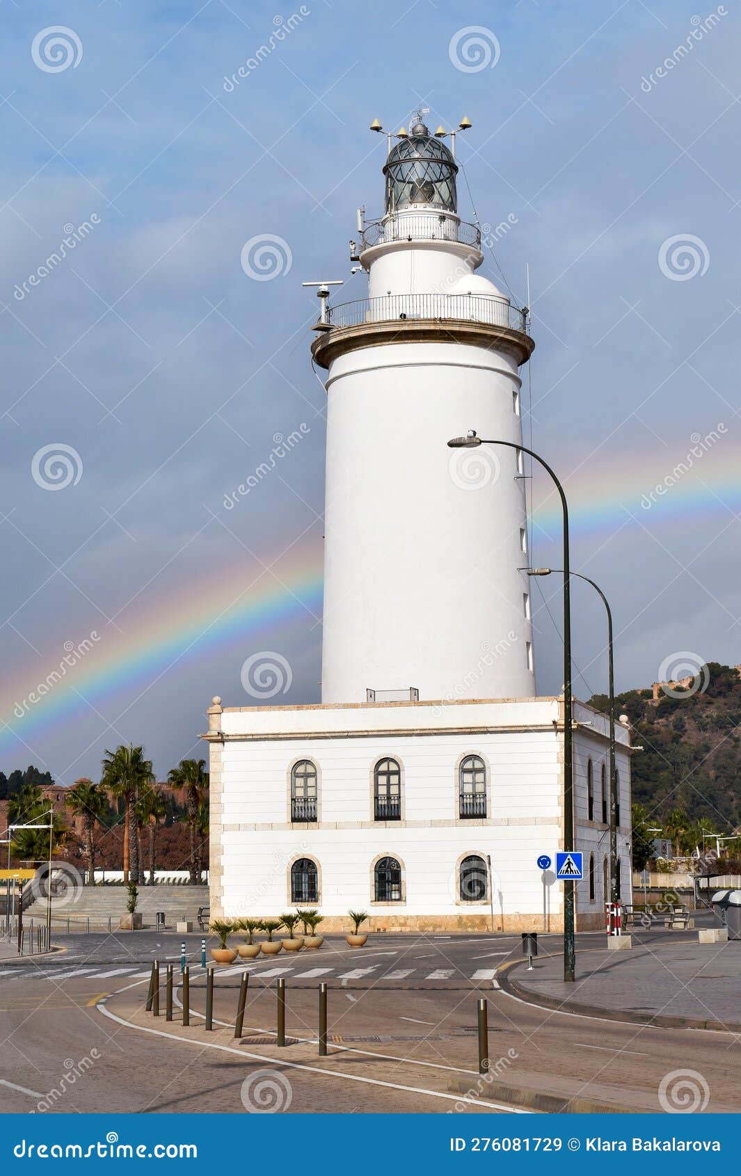 la farola lighthouse in malaga, an old coastal building in the harbour, with a rainbow in the background, spain