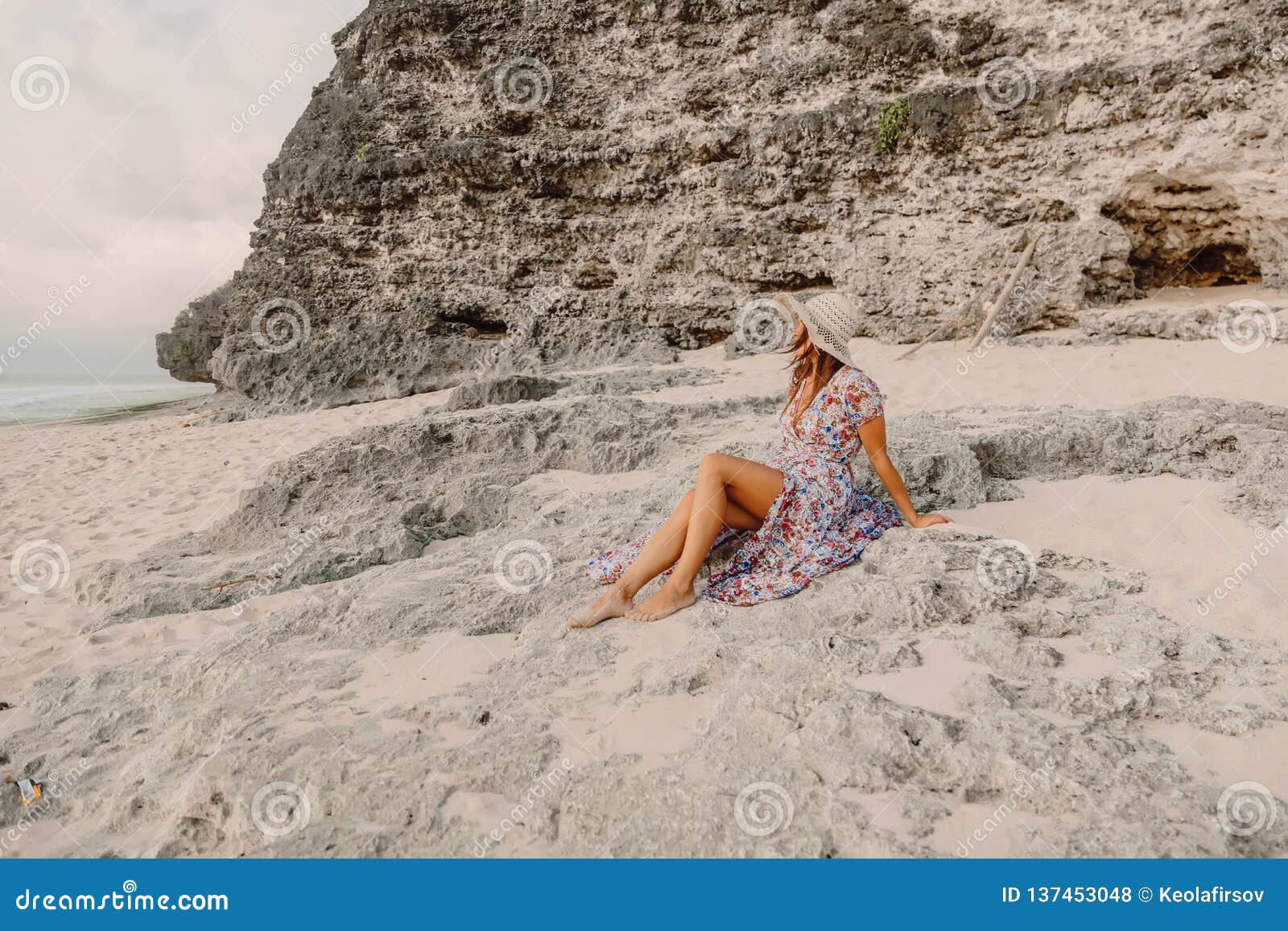 La femme élégante dans la robe d'été s'asseyent sur la plage Style féminin pendant des vacances