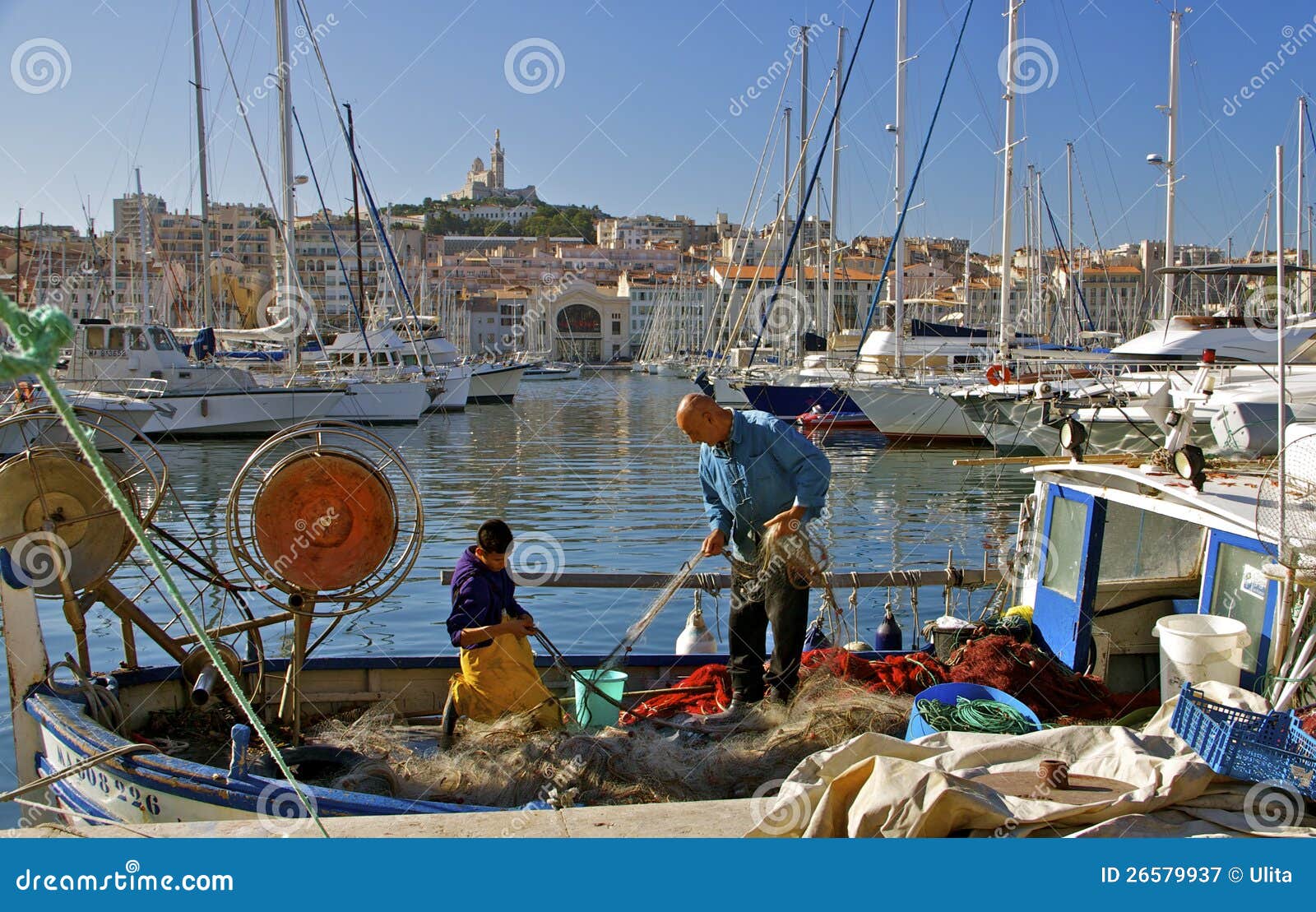 La Garde, Marseille för gammal port och Notre Dame de. Fiskare i den gammala porten av Marseille, Frankrike. I den Garde för bakgrundsNotre Dame de la basilicaen.