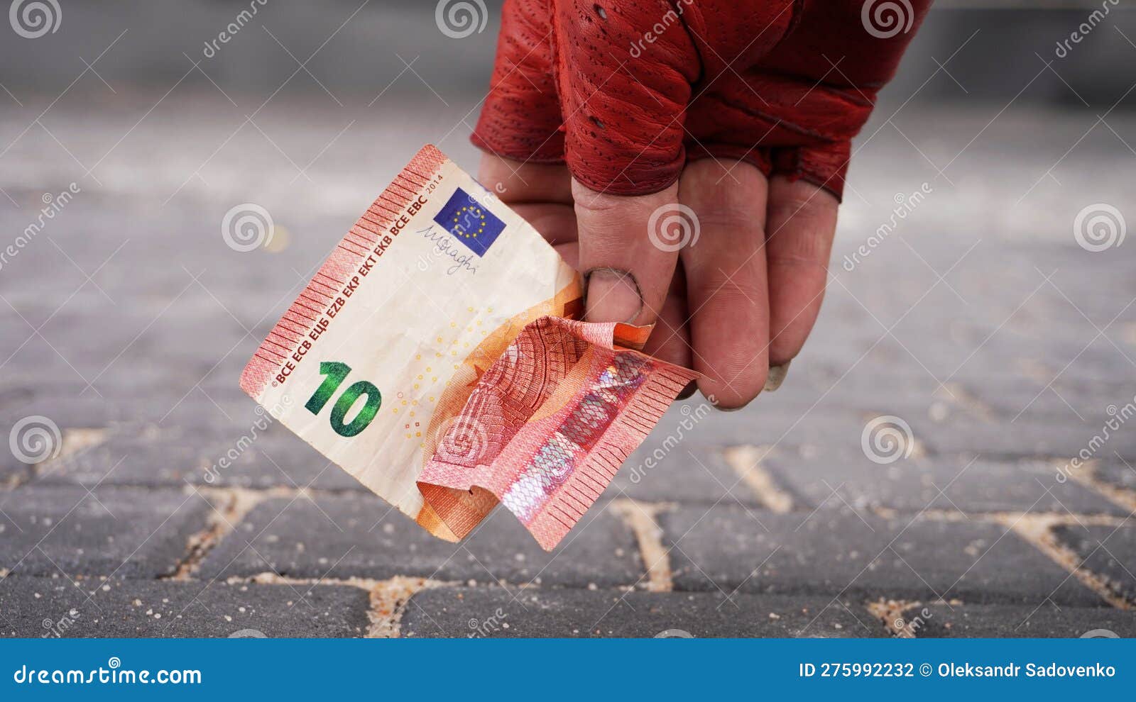 la mano de tramp con un guante rojo levanta un billete de diez euros