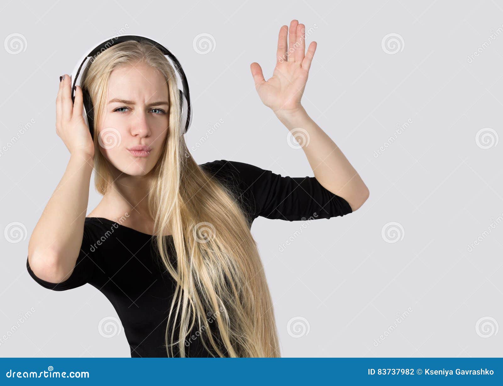 La muchacha adolescente que escuchaba la música en los auriculares aisló el fondo blanco. Chica joven en auriculares que escucha la música y el baile aislada en el fondo blanco Copie el espacio