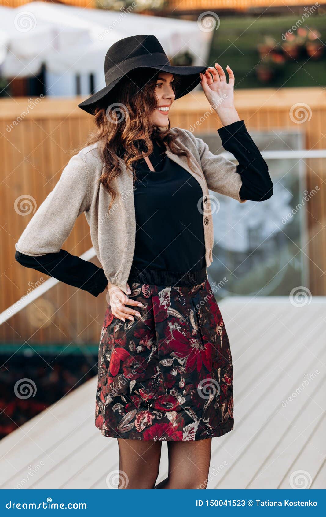 La Muchacha Elegante Vestida En Un Cuello Alto Negro, Un Cabo Beige, Una Corta Elegante Y Un Sombrero Negro Con Las Campana Imagen de archivo - Imagen de calle: 150041523