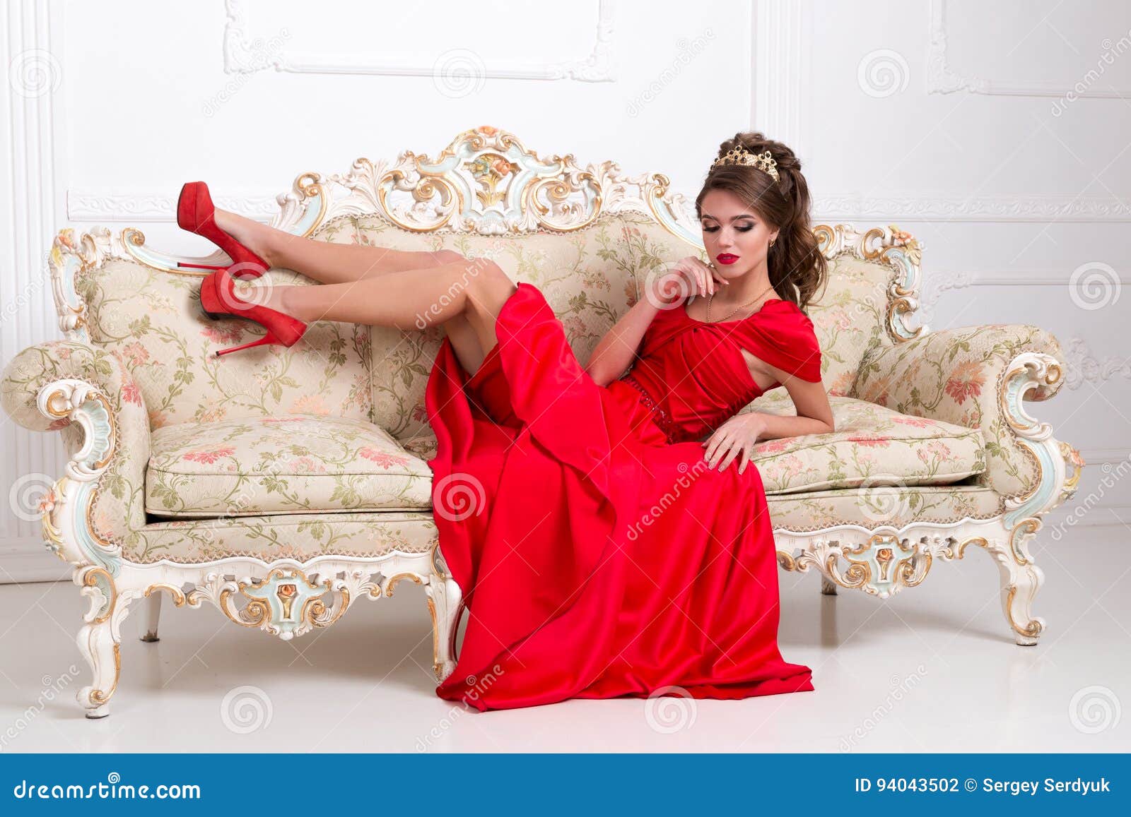 La Muchacha Hermosa En Un Vestido Rojo Largo Y Zapatos Miente En Un V Foto de - Imagen lujo, estudio: 94043502