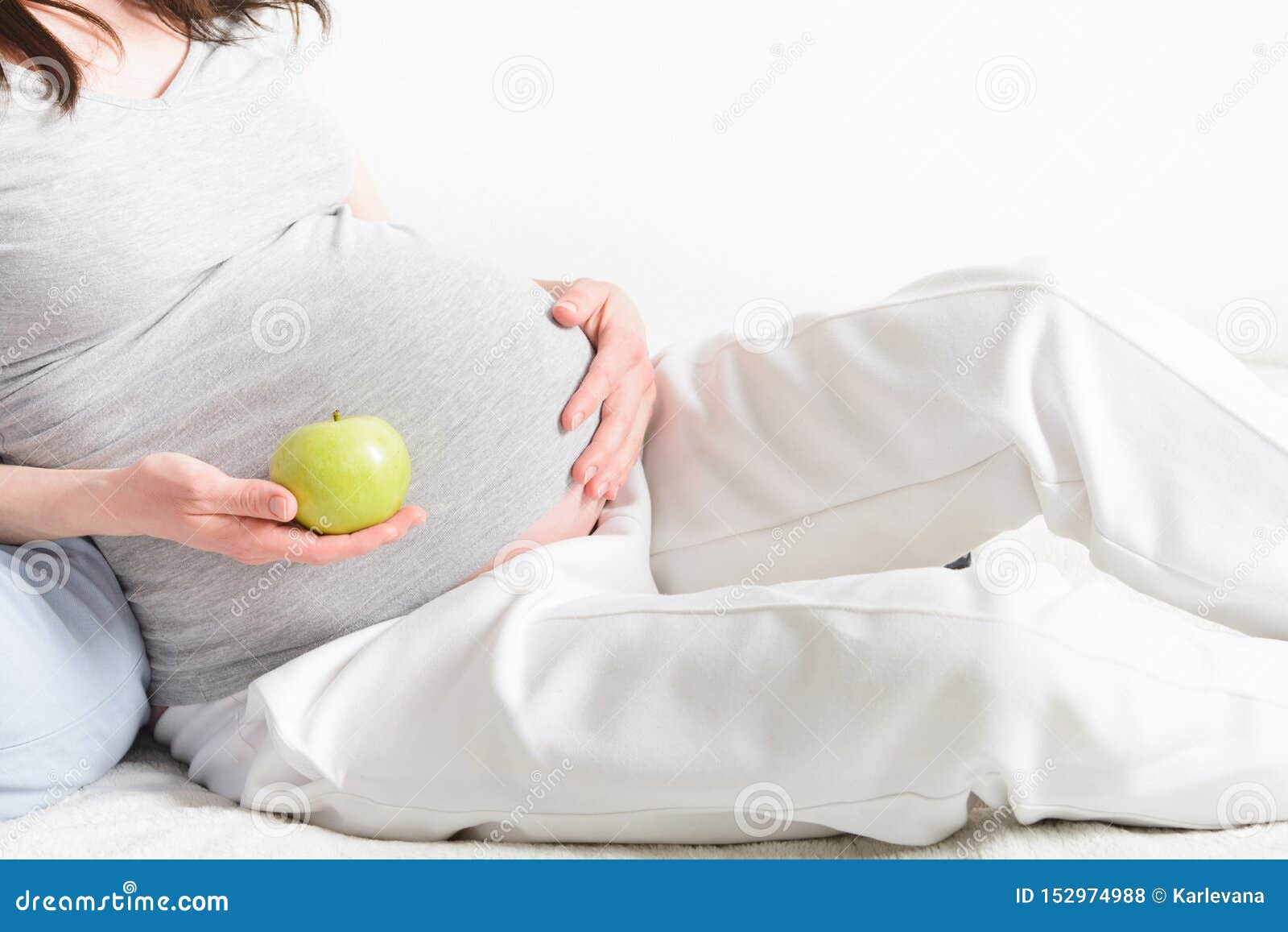 La Mujer Embarazada Está Contando Con a Un Bebé Con La Manzana Verde Natural En La Mano Concepto Del Cuidado M?dico Copie Espa Foto de - Imagen comida, desayuno: