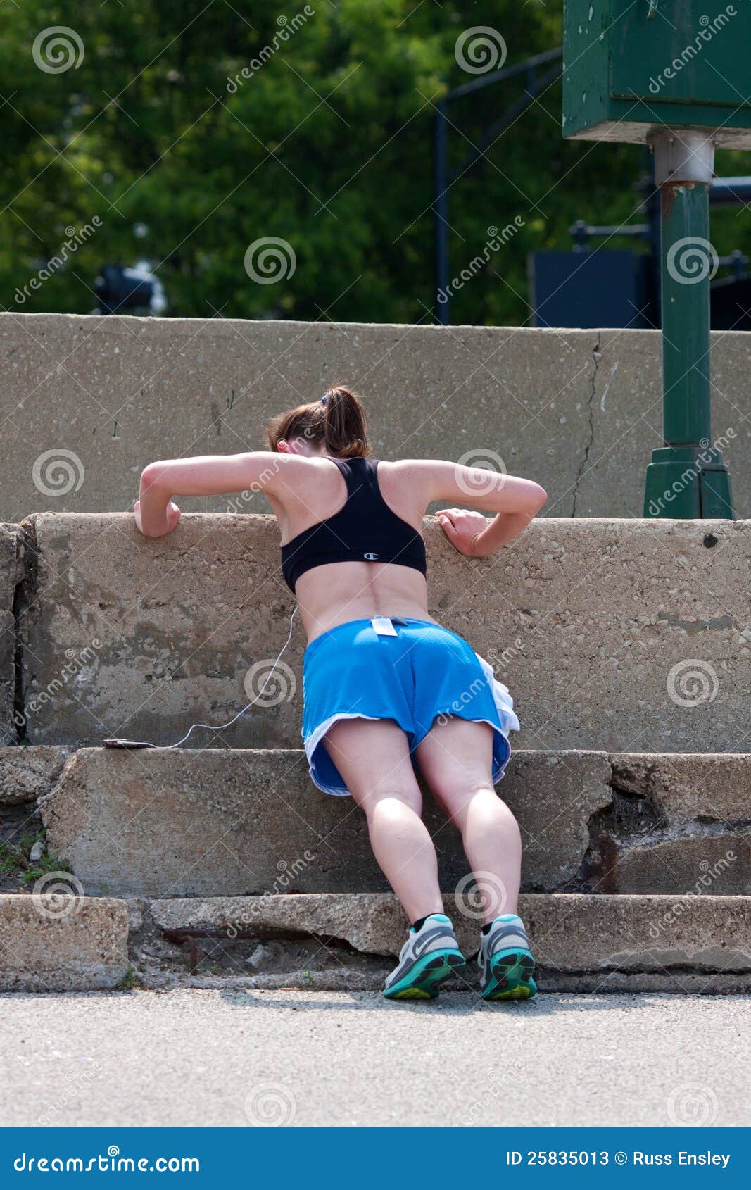 La mujer joven hace pectorales contra pasos de progresión concretos. CHICAGO, IL - 26 DE MAYO: Una mujer joven no identificada hace pectorales contra pasos de progresión concretos en un área pavimentada que separa el mecanismo impulsor y el lago Michigan de la orilla del lago chicago's. Fin de semana el tiempo y del día de fiesta calientes del Memorial Day trajeron a millares de gente hacia fuera a orillas del lago al área famosa del mecanismo impulsor.