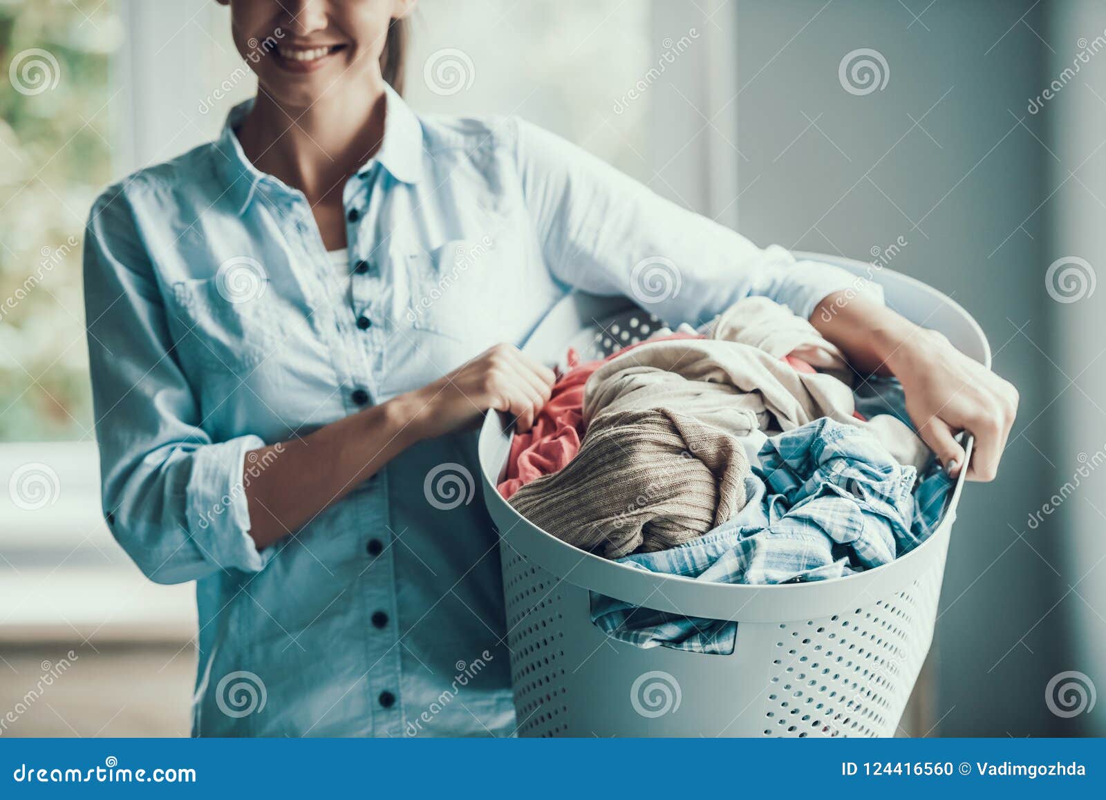 La Mujer Sonriente Joven Sostiene La Cesta De Ropa Limpia Foto de archivo -  Imagen de casa, secador: 124416560