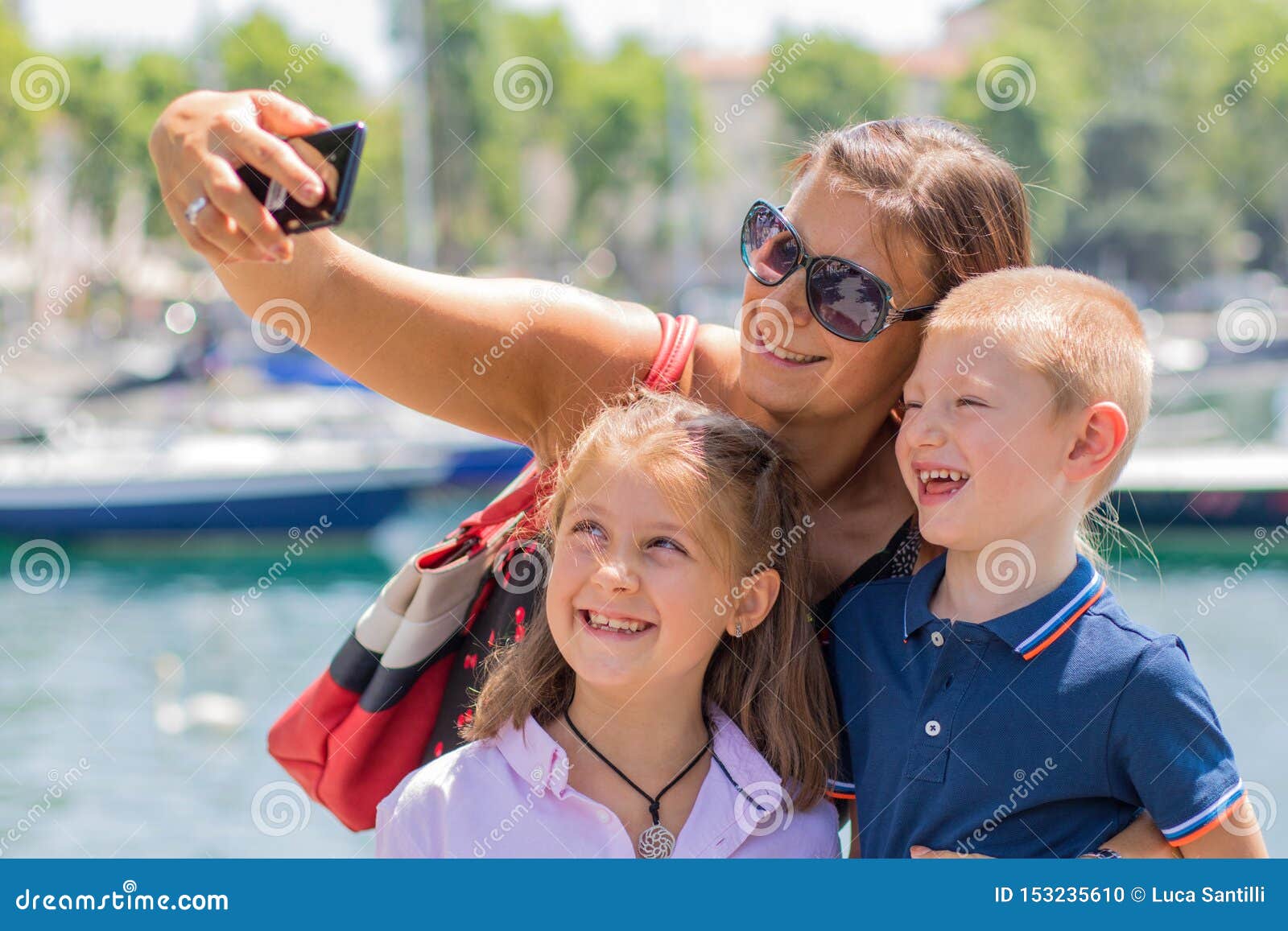 La mère heureuse avec ses enfants prennent un selfie dans un jour ensoleillé