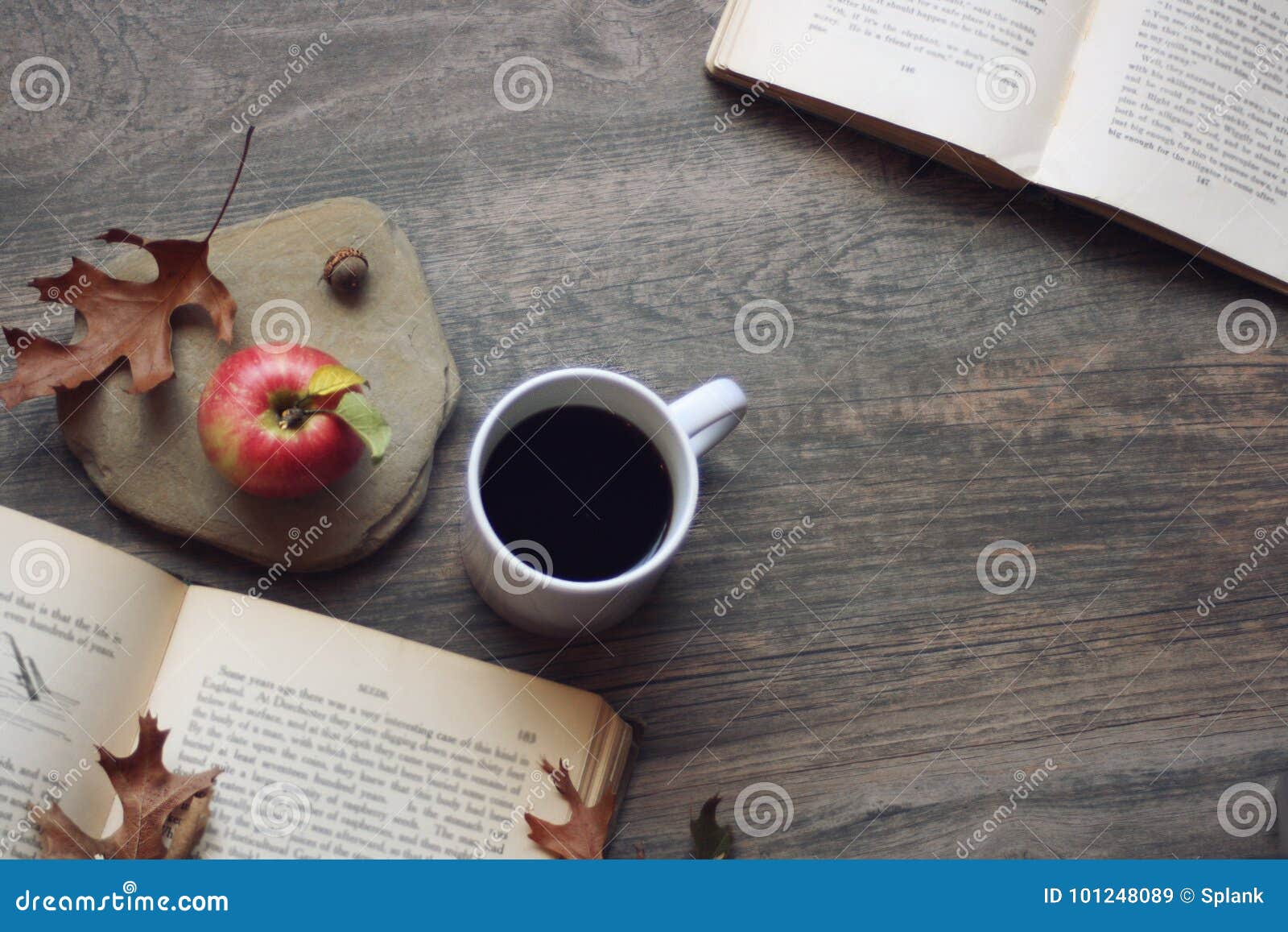 La natura morta di autunno con la mela, il caffè, libri aperti e rimane il fondo di legno rustico, lo spazio della copia, l'orizz