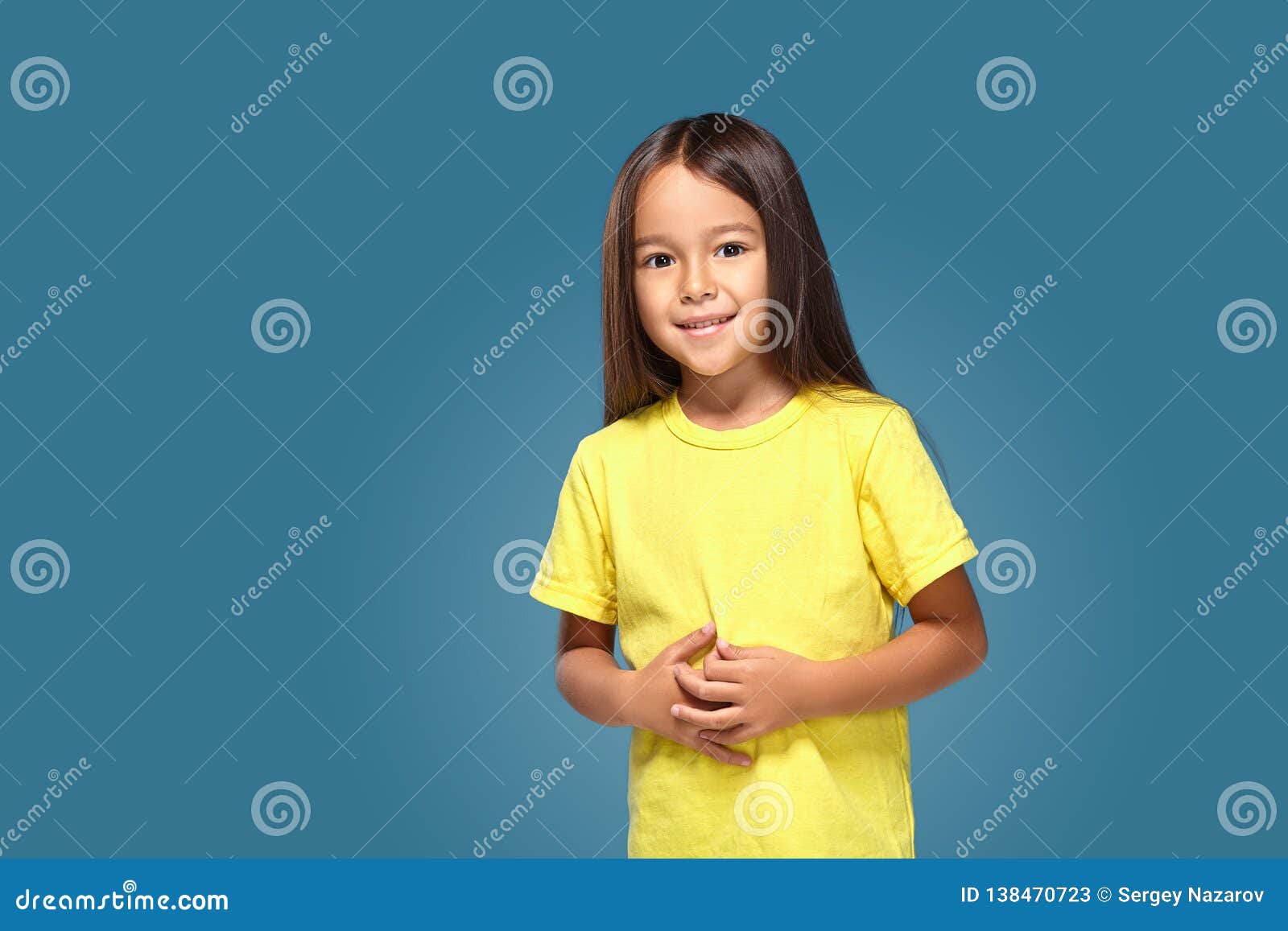 La Niña En Camiseta Amarilla Está Sonriendo Imagen de archivo