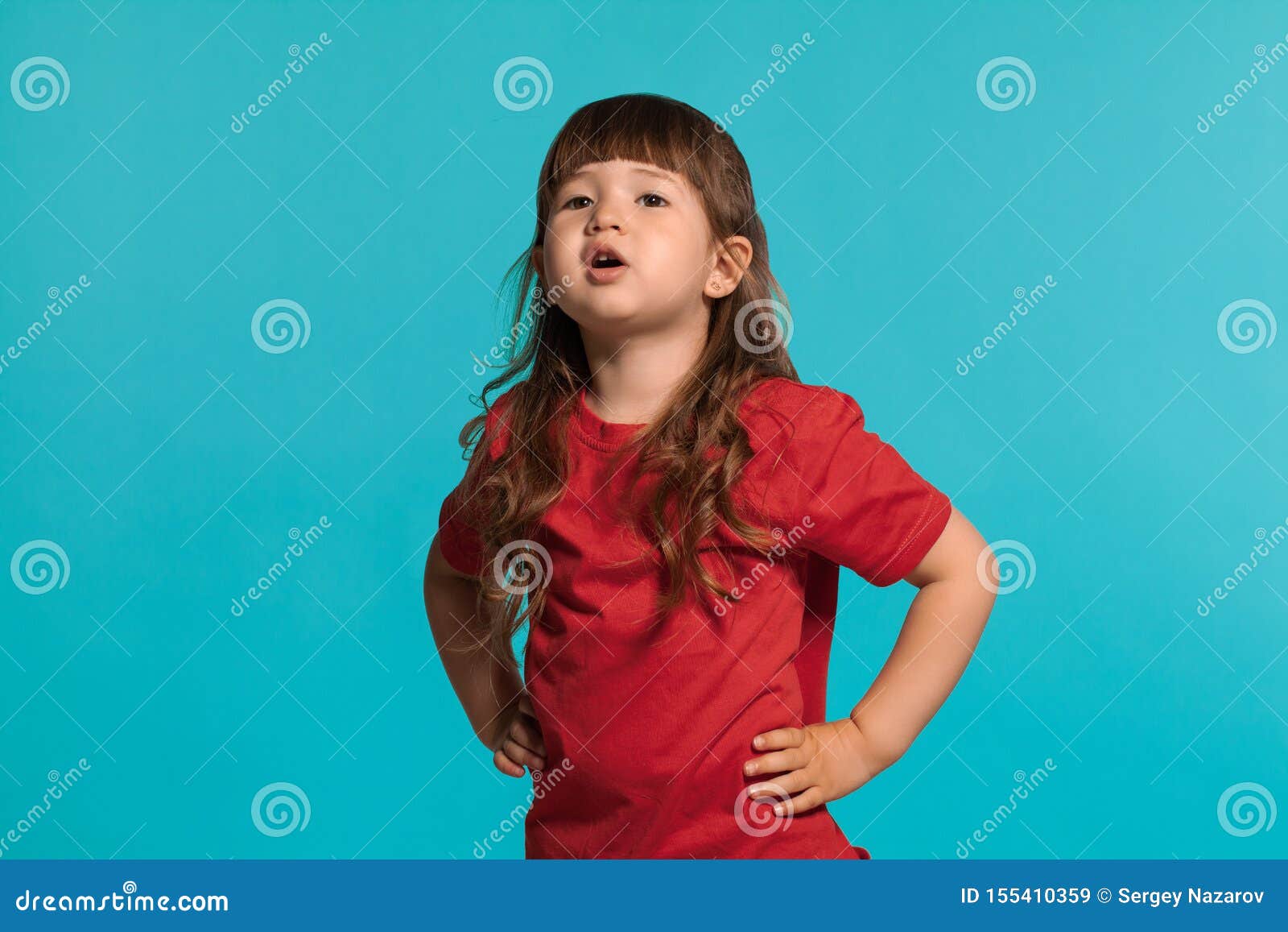 La Niña Hermosa Que Lleva En Una Camiseta Roja Presentando Contra Un Fondo Azul Del Estudio Imagen de archivo - Imagen de hembra, manera: 155410359