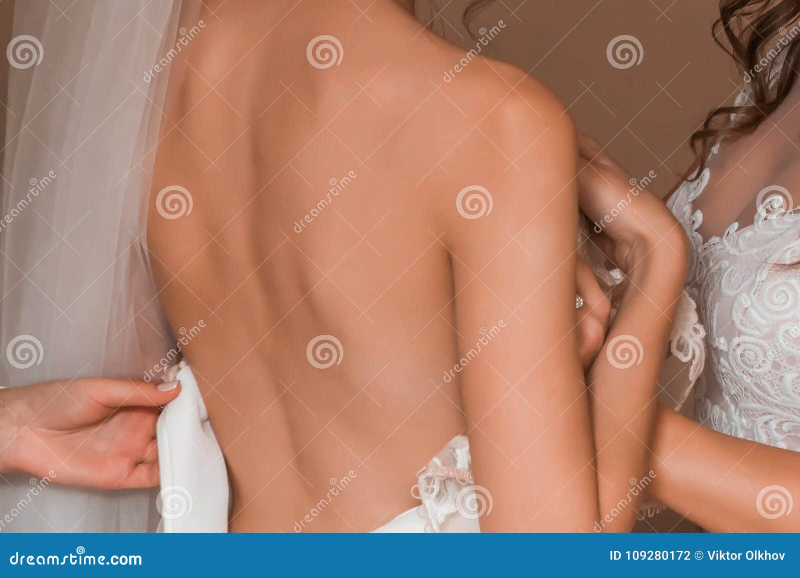 La Novia Con Una Parte Posterior Desnuda, Llevando Un Vestido De Boda, Y La Muestra Su Manga Foto de archivo